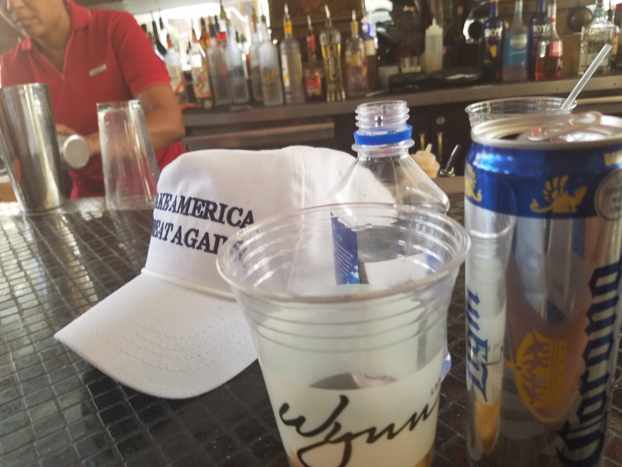 a cap and plastic cups on a bar counter