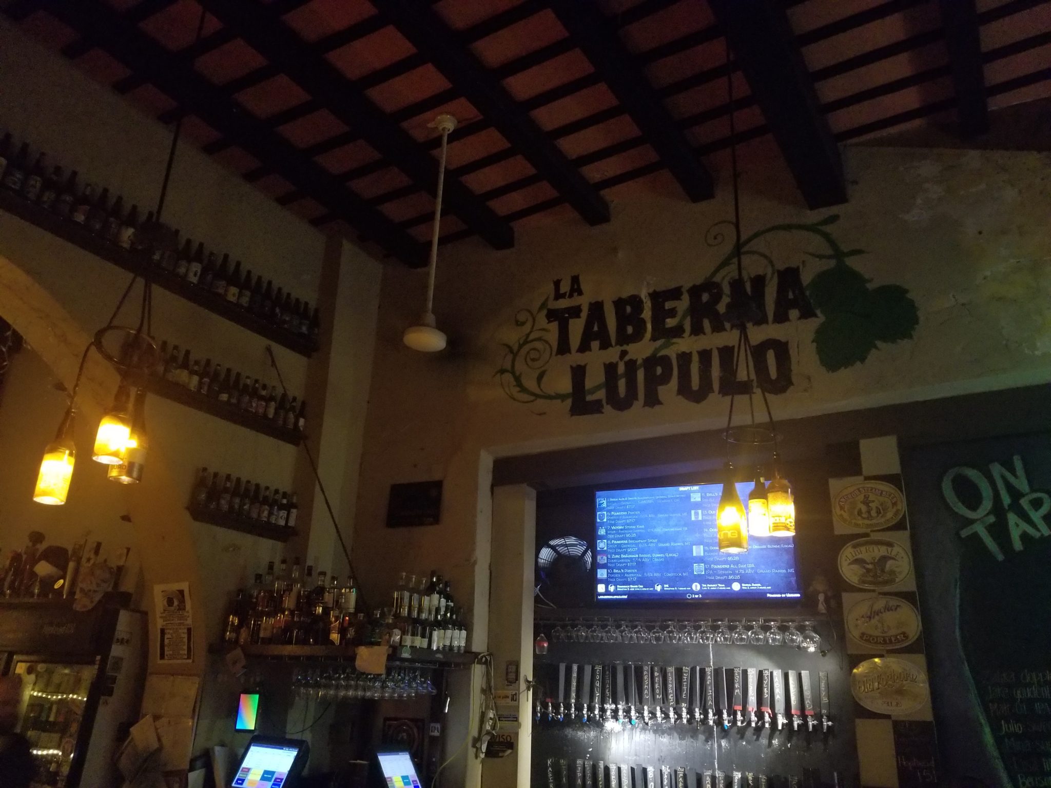 a bar with a screen and beer bottles