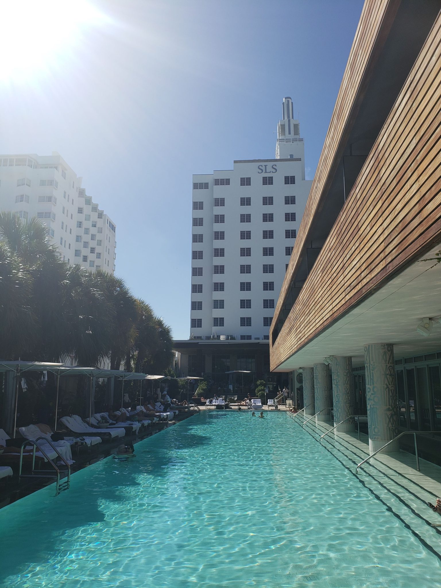 a pool with chairs and a building in the background