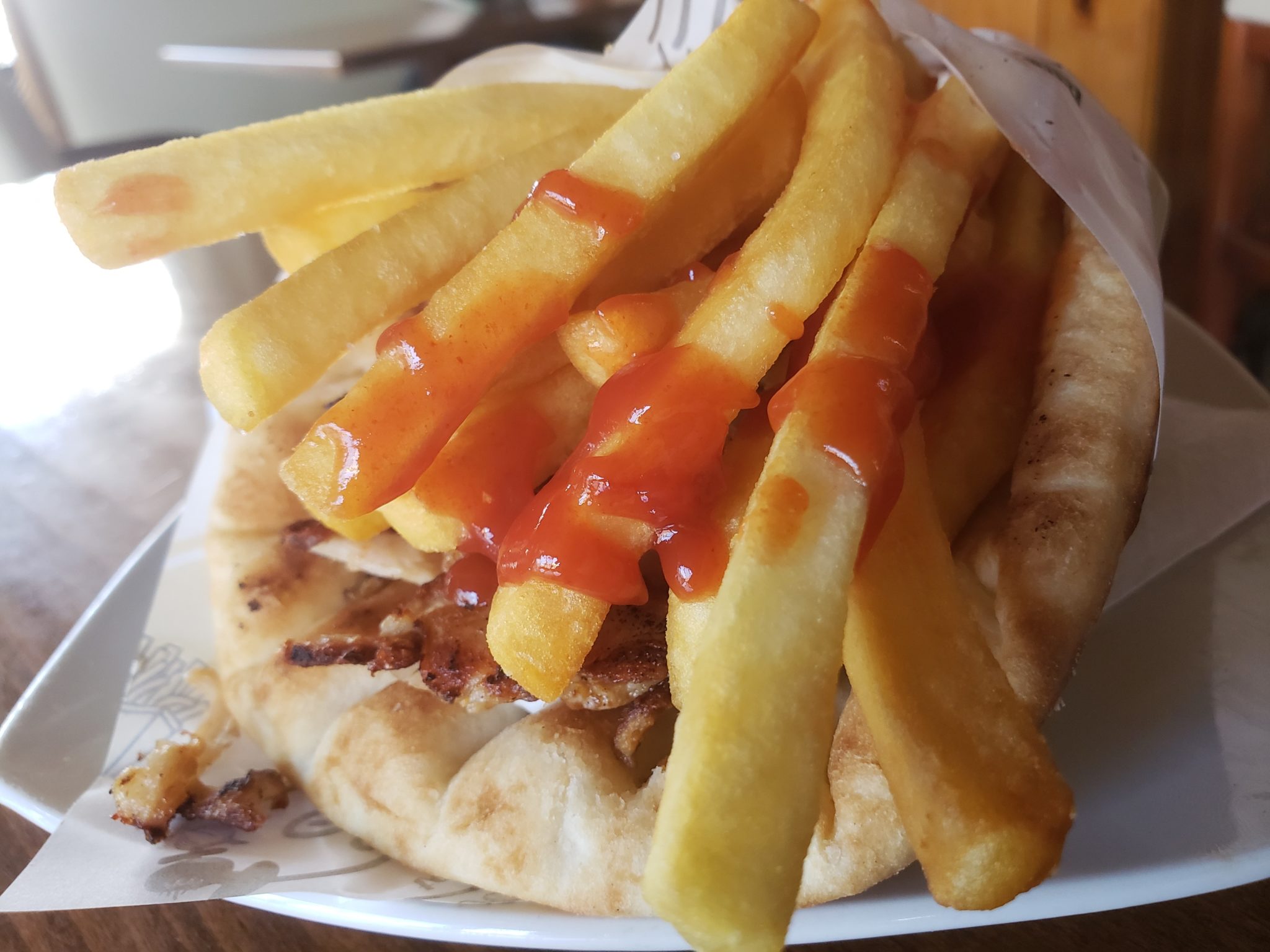 a pita bread with french fries and ketchup on top