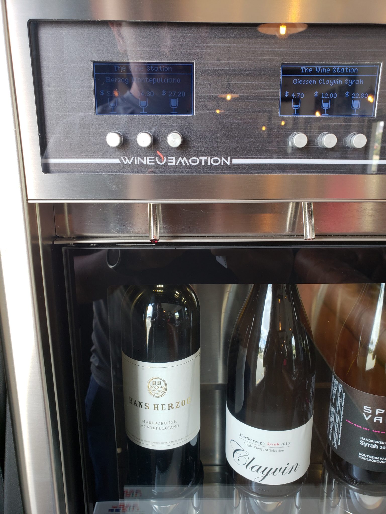 a wine cooler with a display and bottles of wine