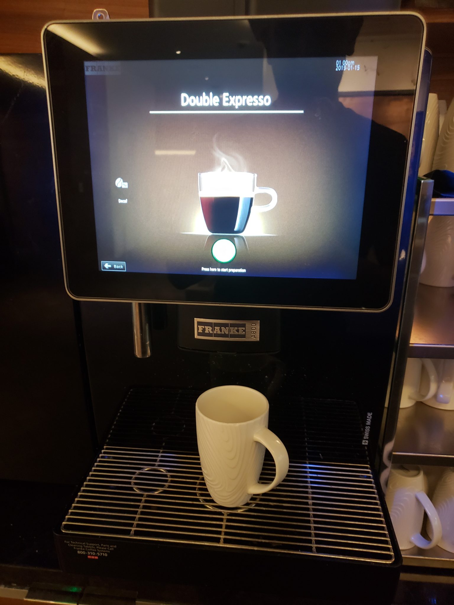 a coffee machine with a screen and a mug