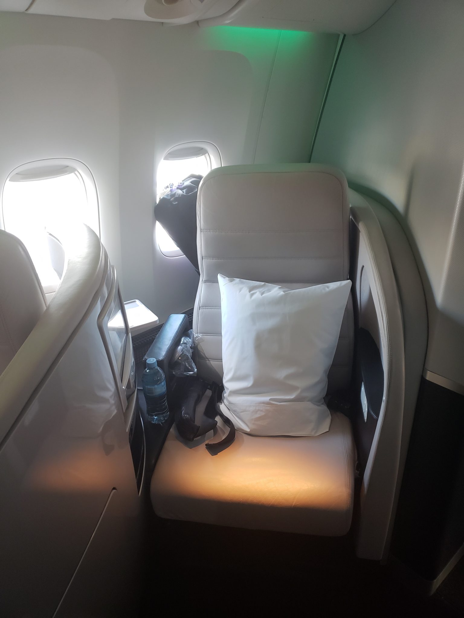 a seat with a pillow and a bottle on the side of it