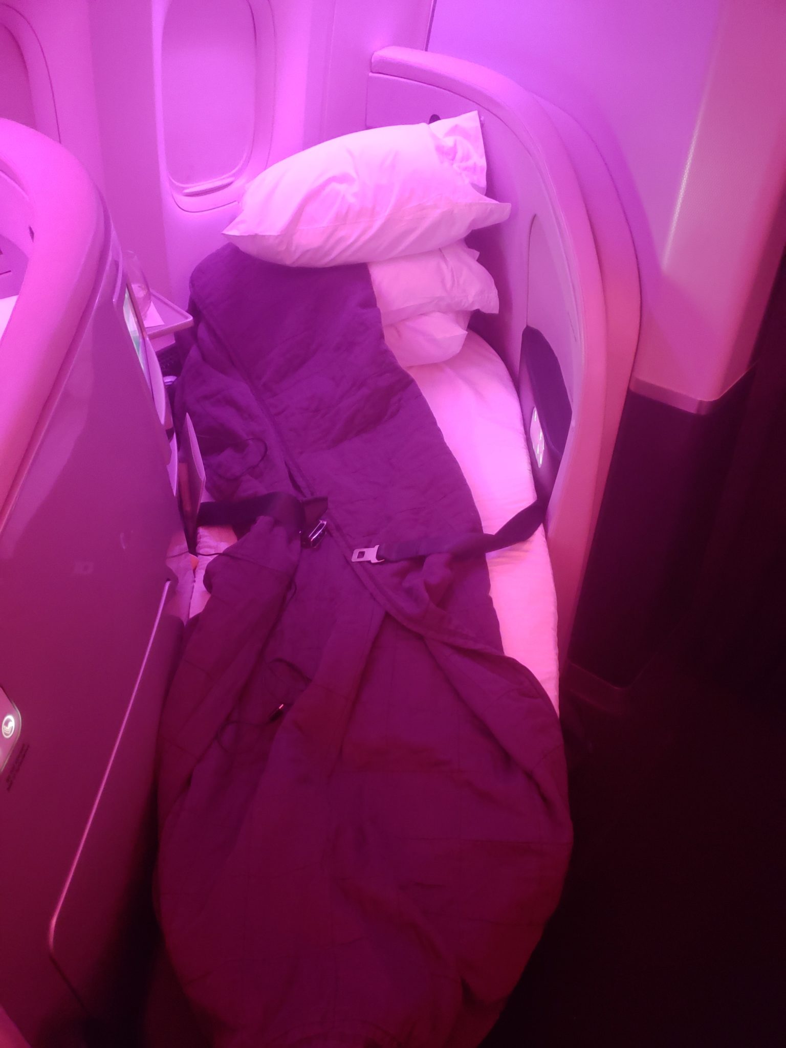 a bed with a blanket and pillows in a plane