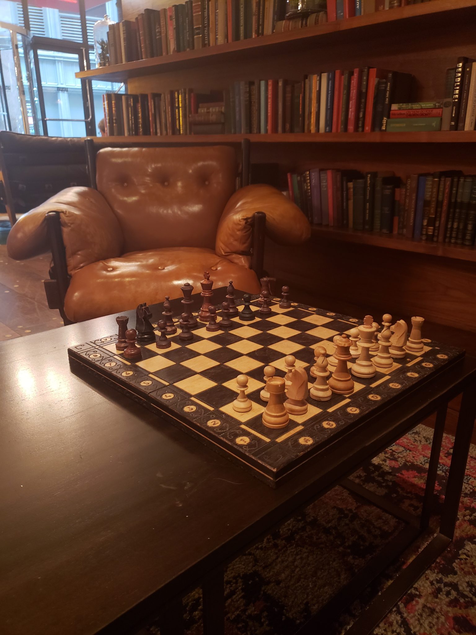 a chess board on a table in front of a leather chair