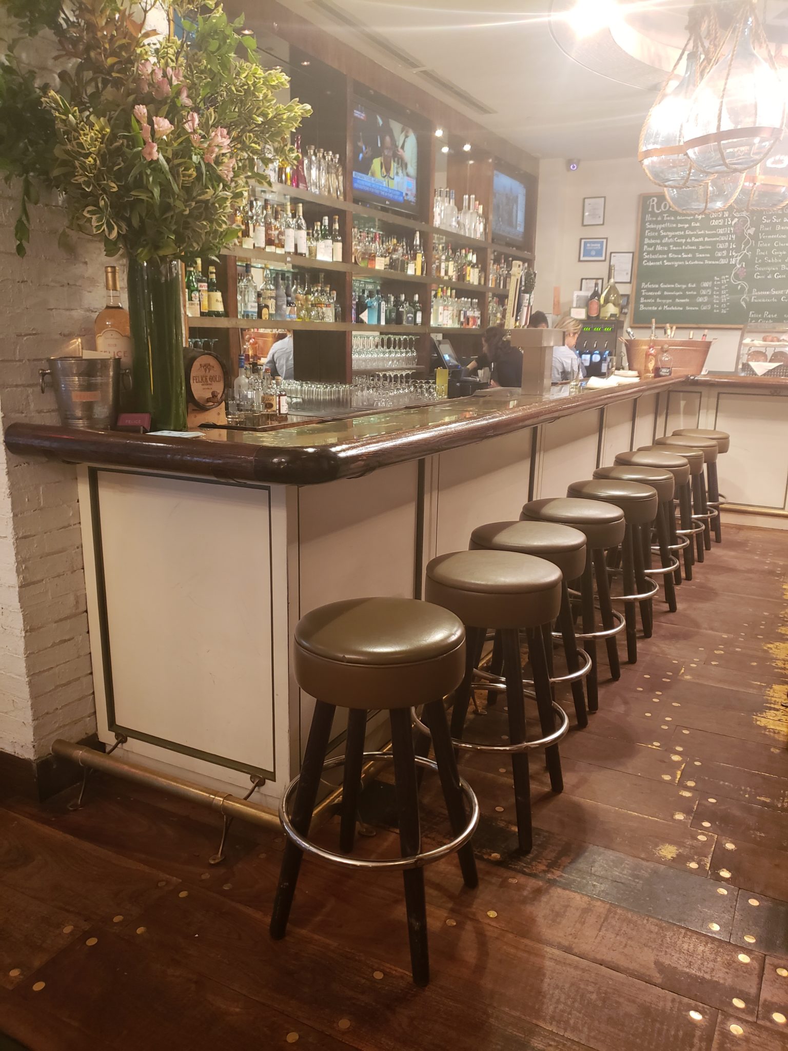a bar with stools and a row of glasses