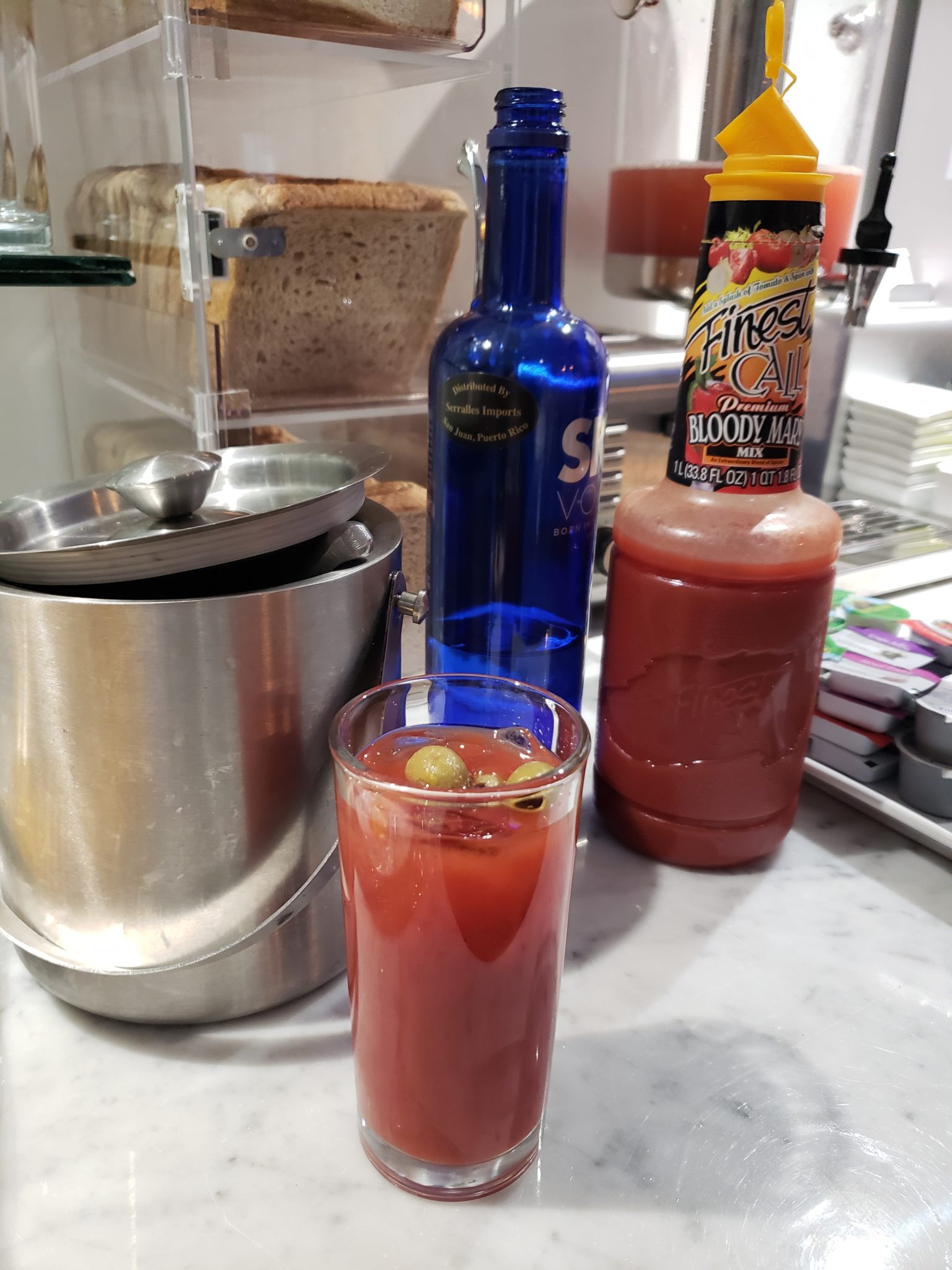 a glass of bloody mary and a blue bottle of liquid