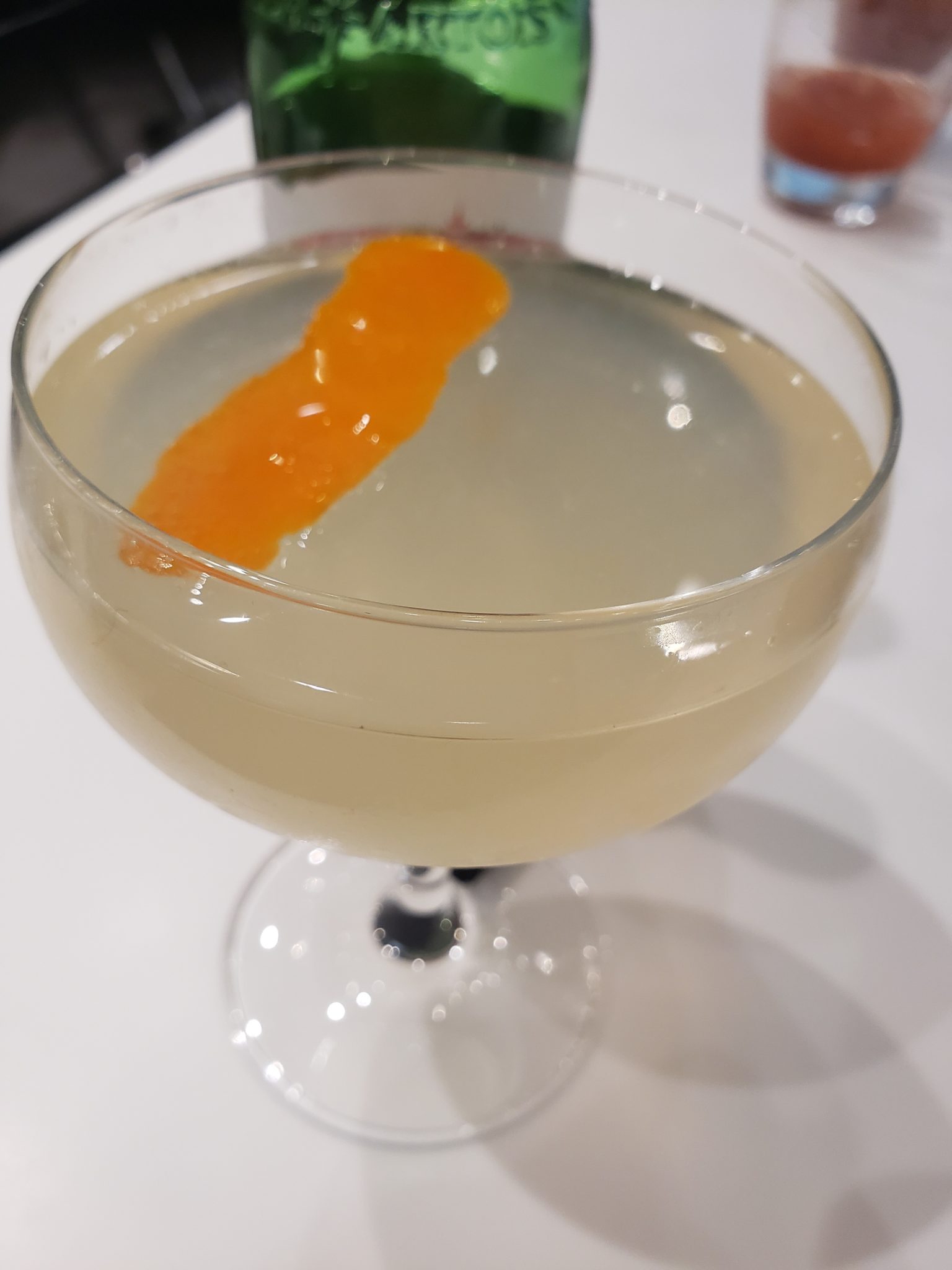 a glass of liquid with an orange peel