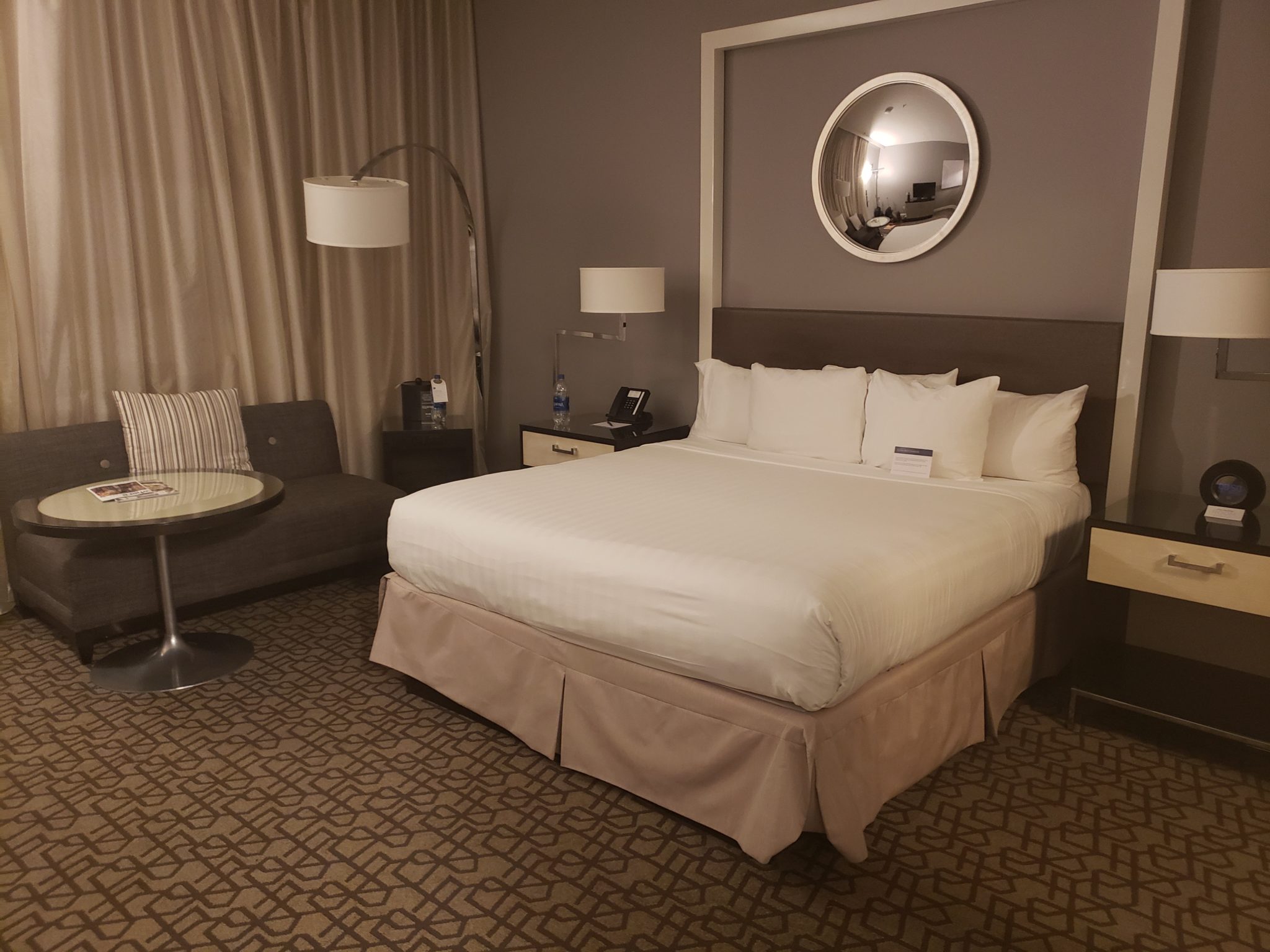 a hotel room with a bed and a round mirror