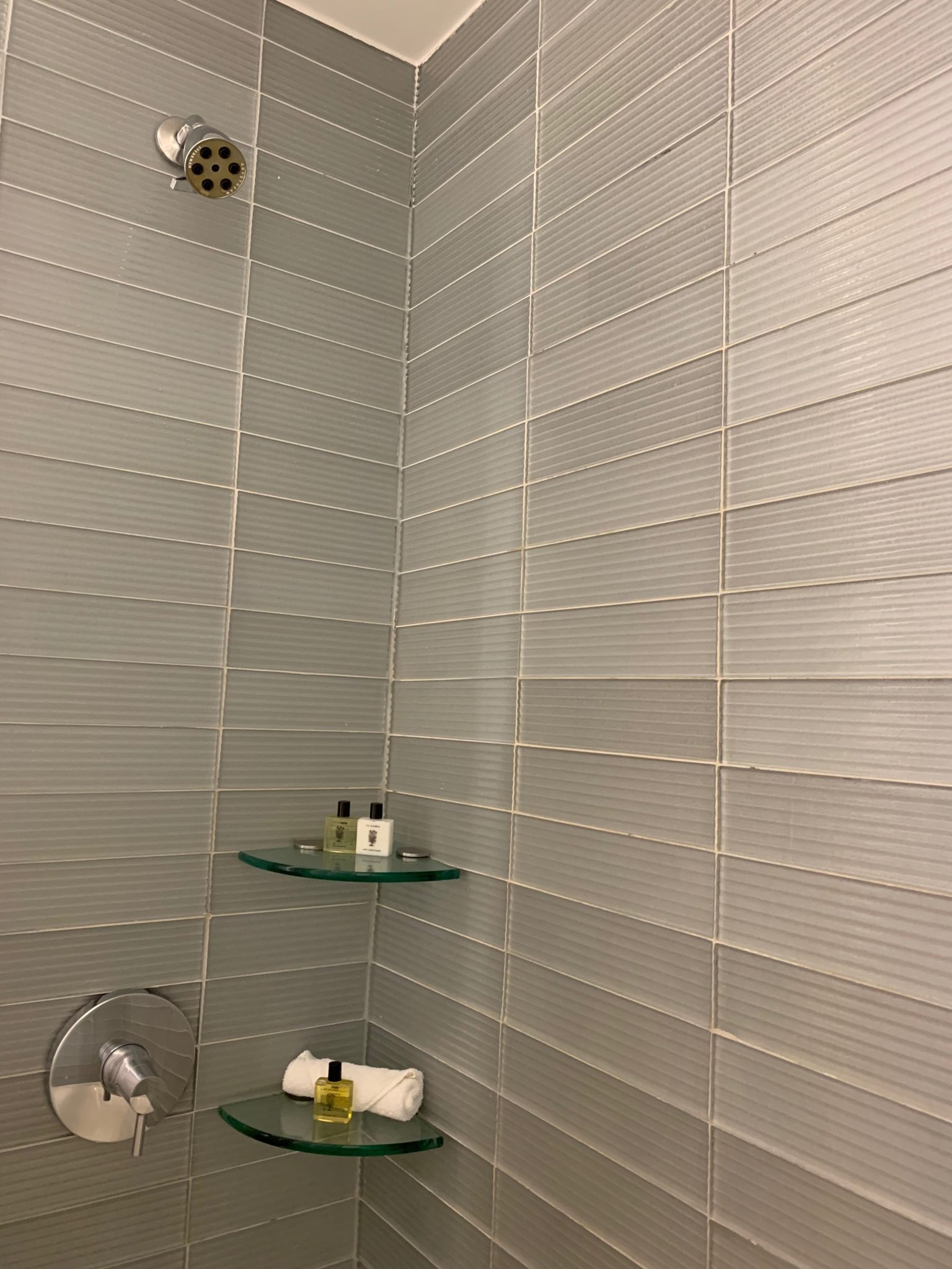 a shower with a shower head and a small shelf