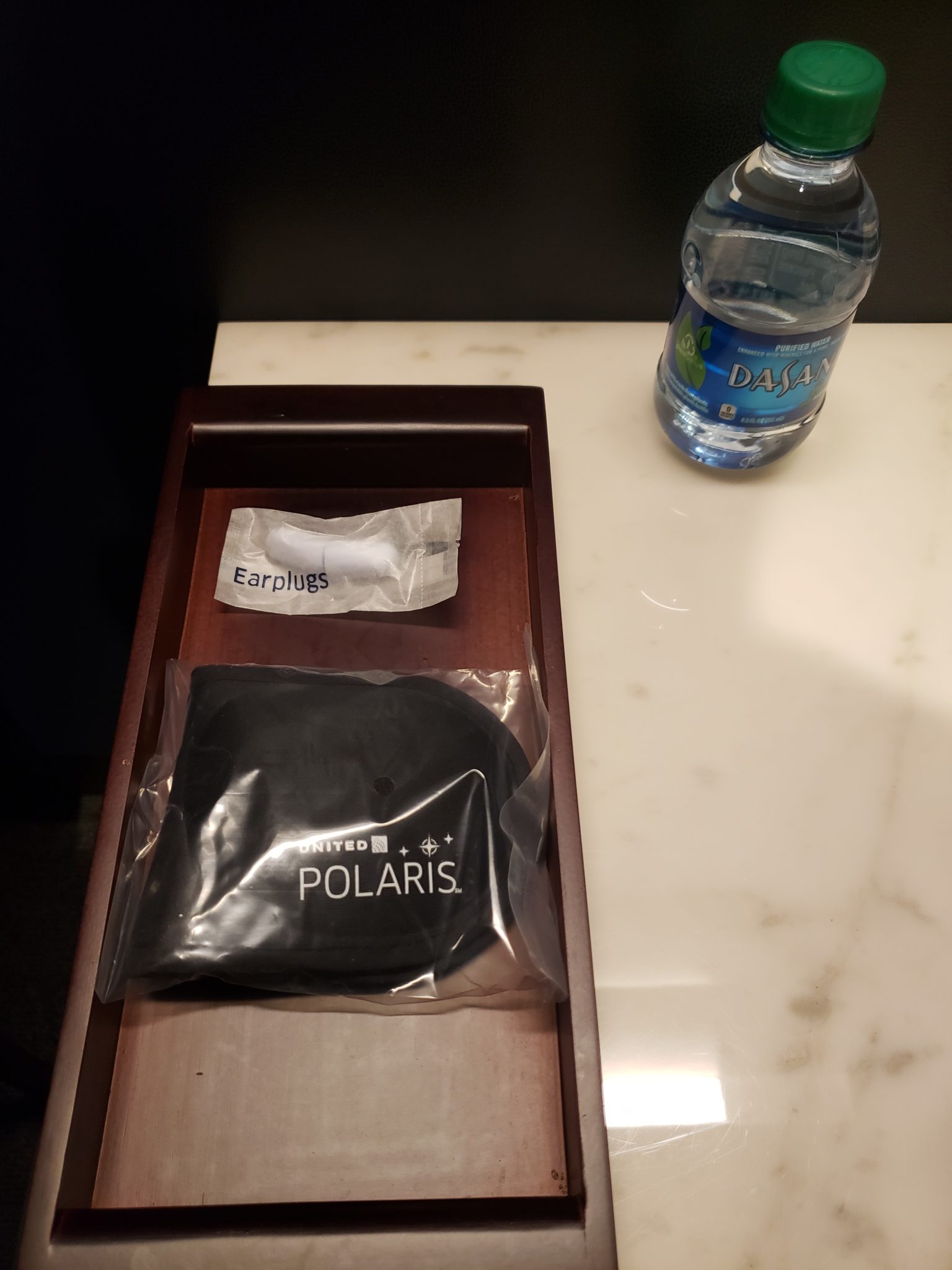 a wooden tray with a bottle of water and a black object on it