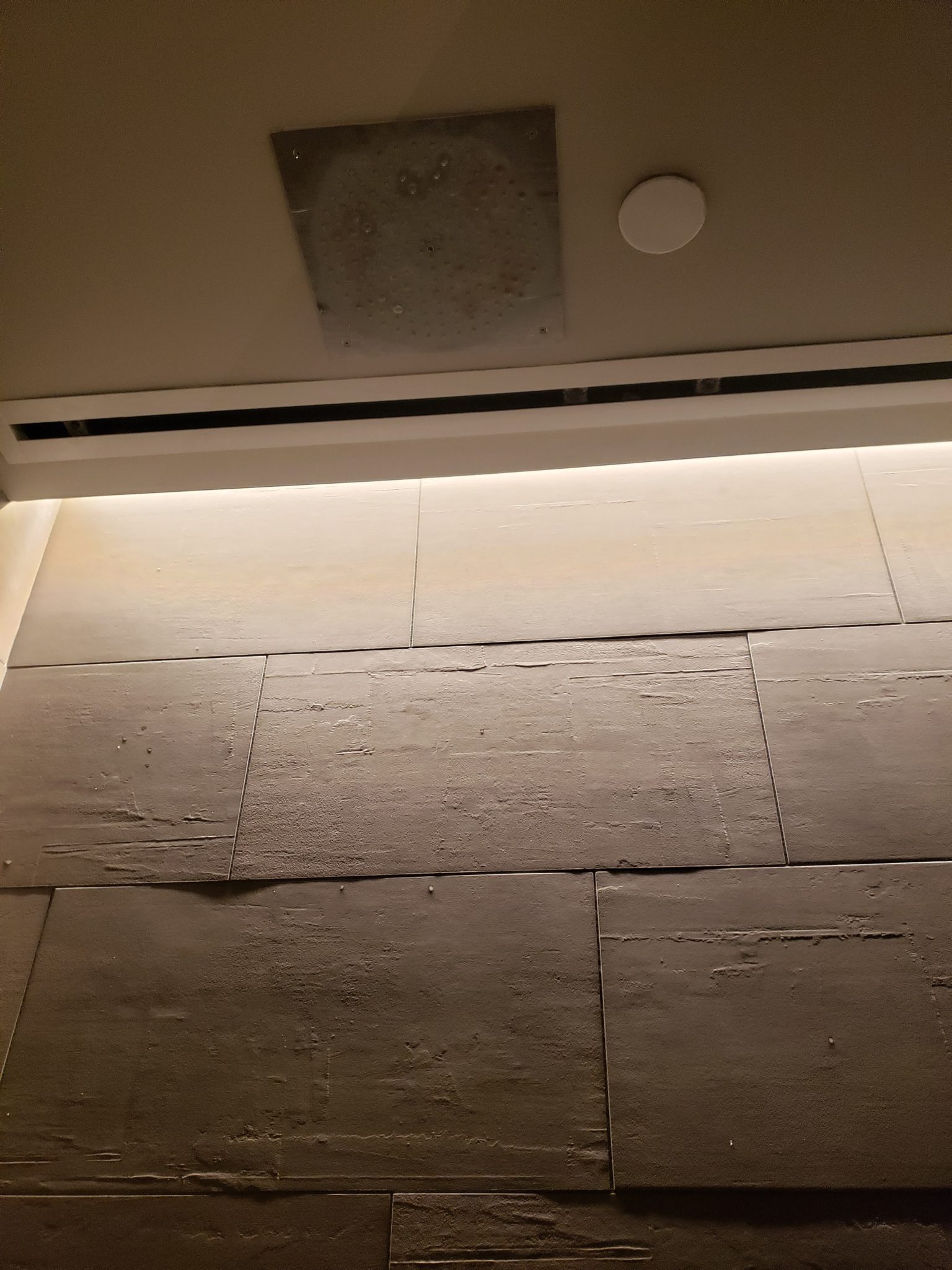 a tile wall with a light on the ceiling