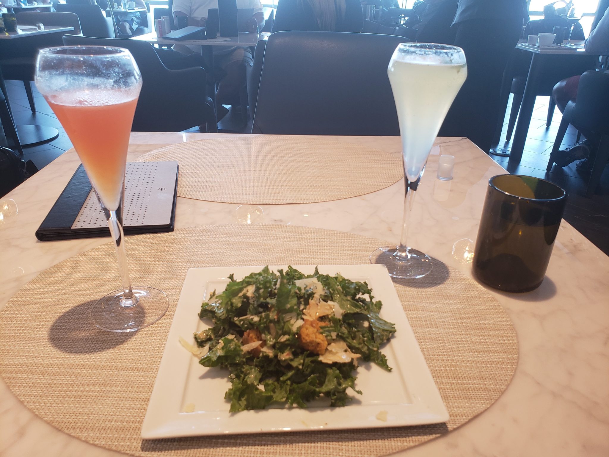 a plate of salad and two glasses of liquid on a table