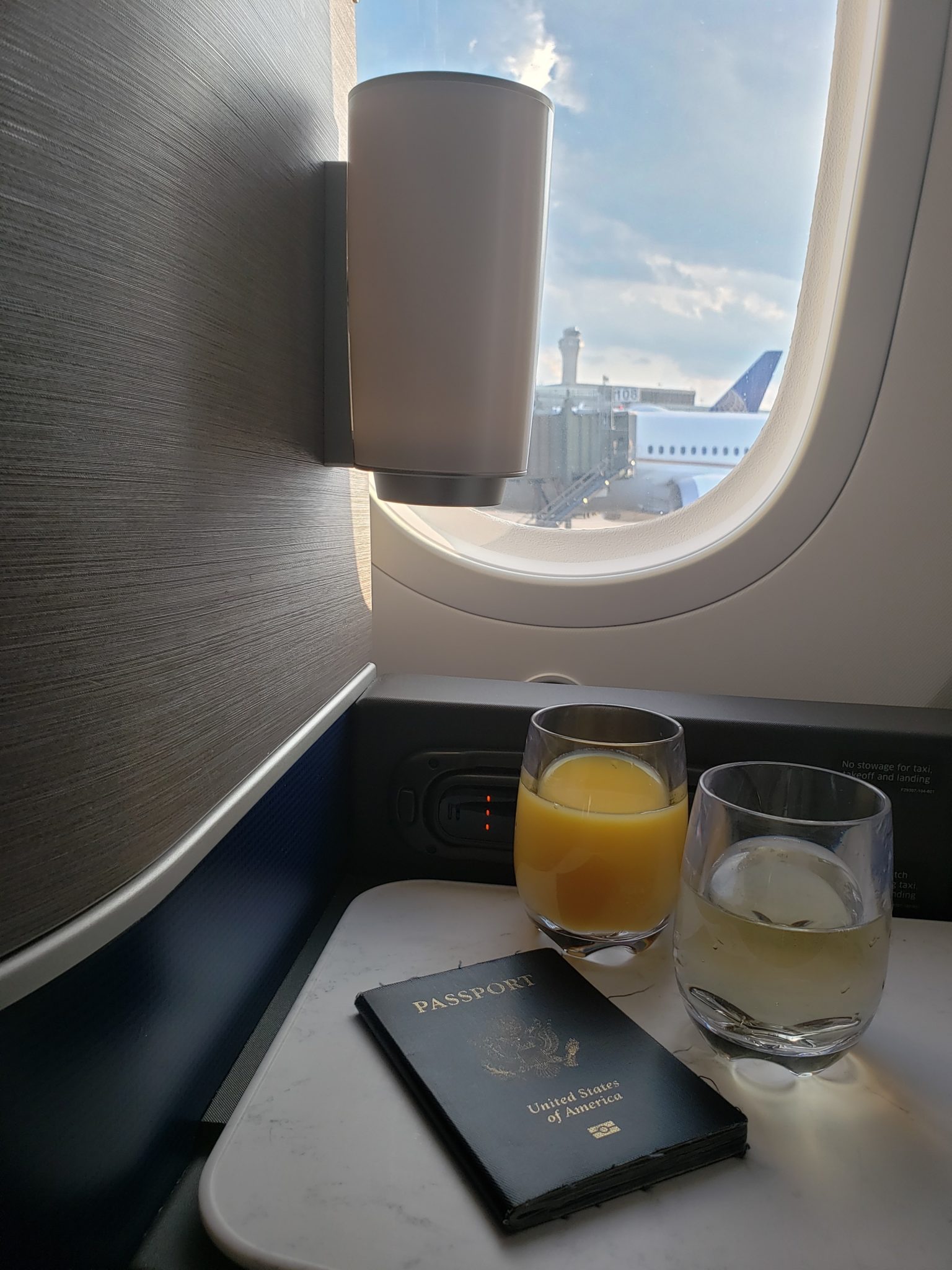 glasses of juice and a passport on a table in an airplane