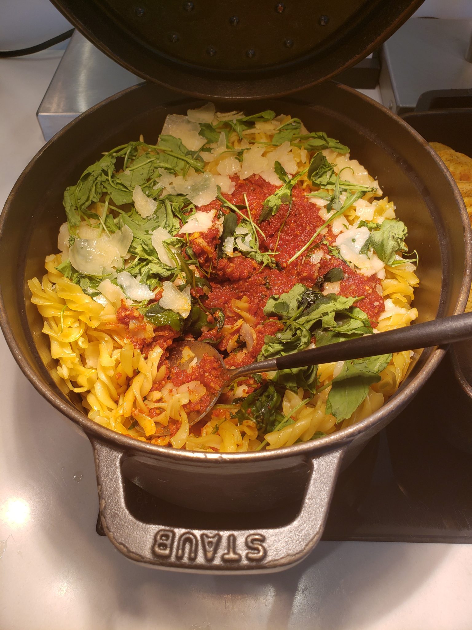 a pot of pasta with sauce and vegetables
