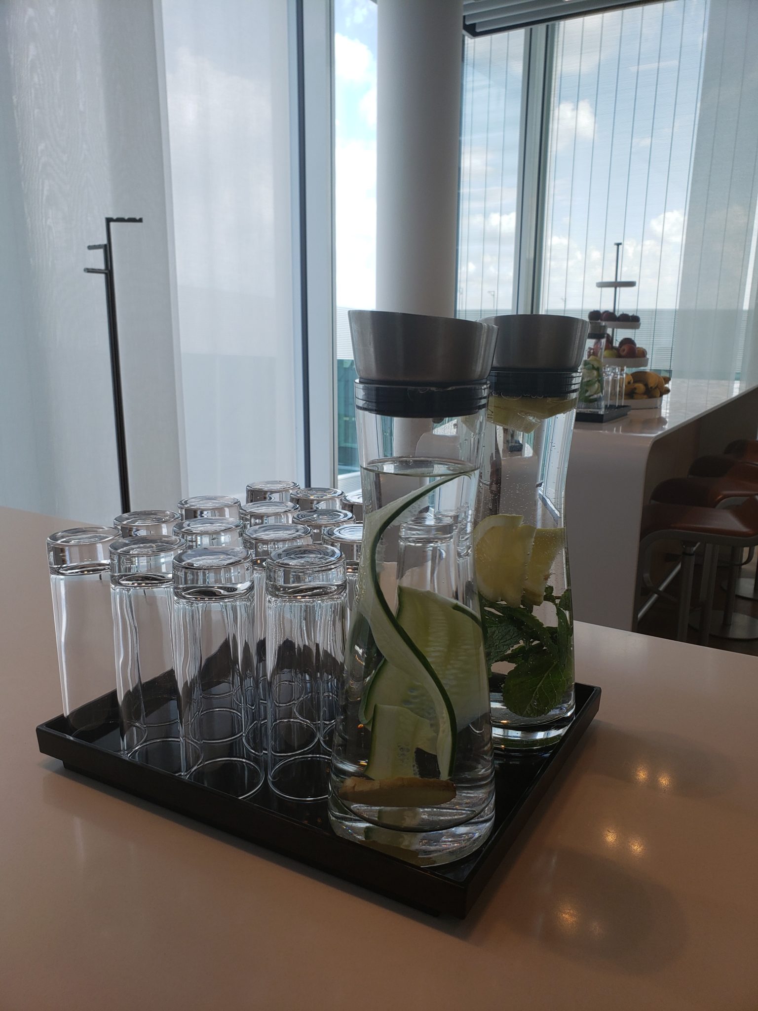 a tray of glasses and a pitcher with water and a cucumber on it