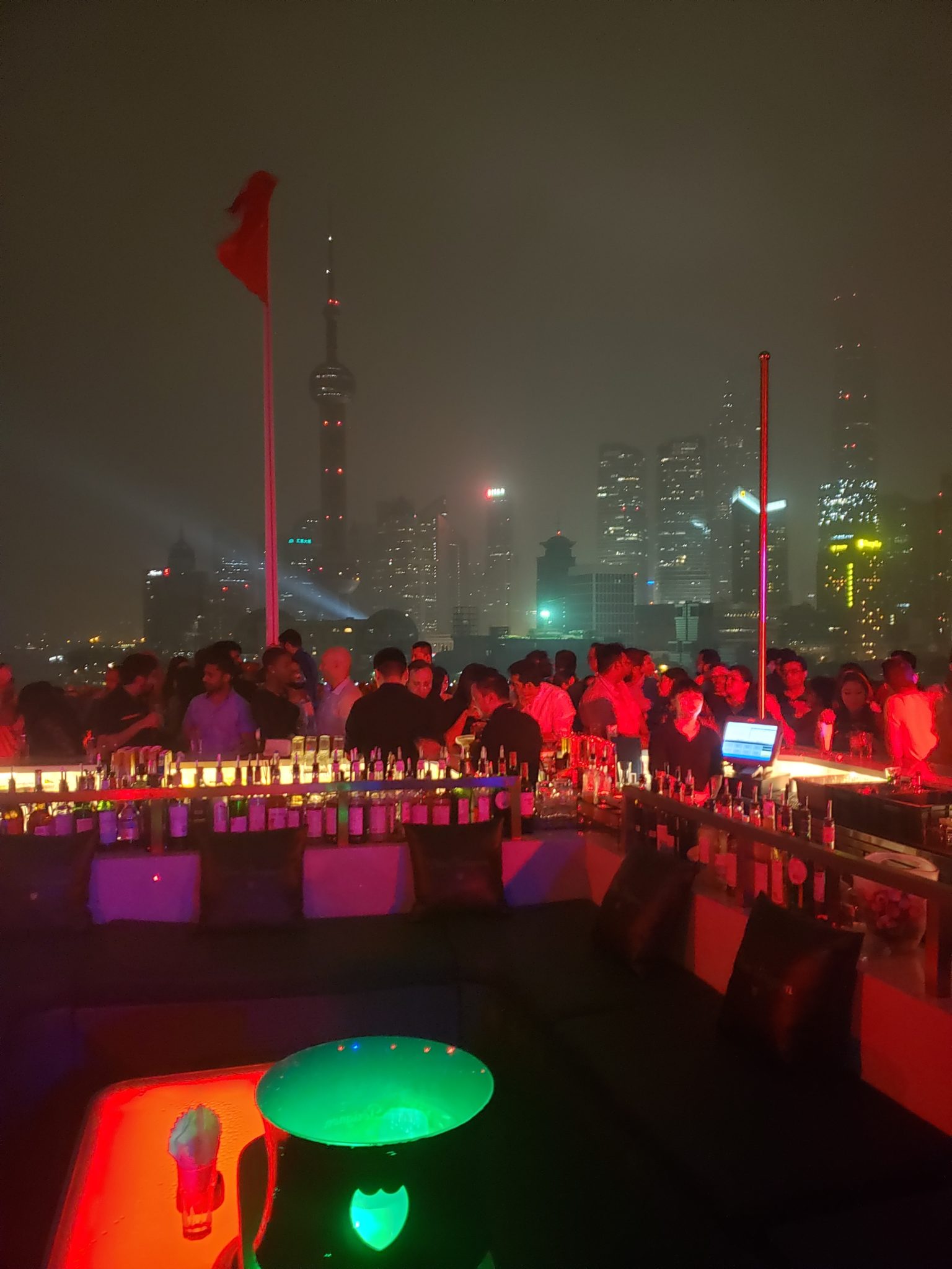 a group of people at a rooftop bar with a city skyline in the background