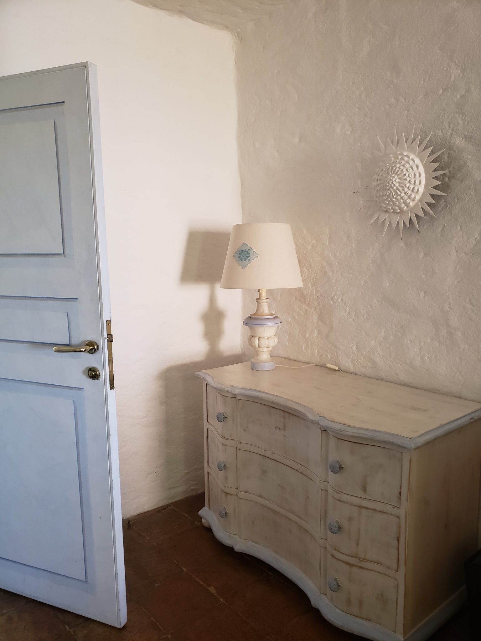 a white dresser with a lamp on it