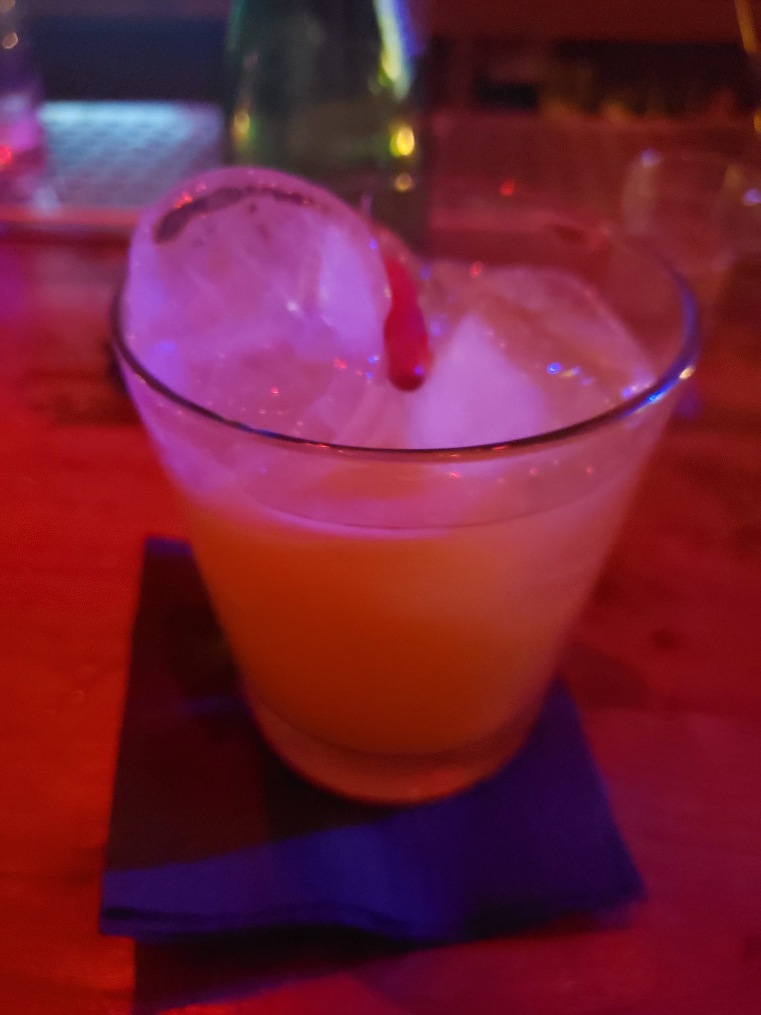 a glass of orange liquid with a straw in it