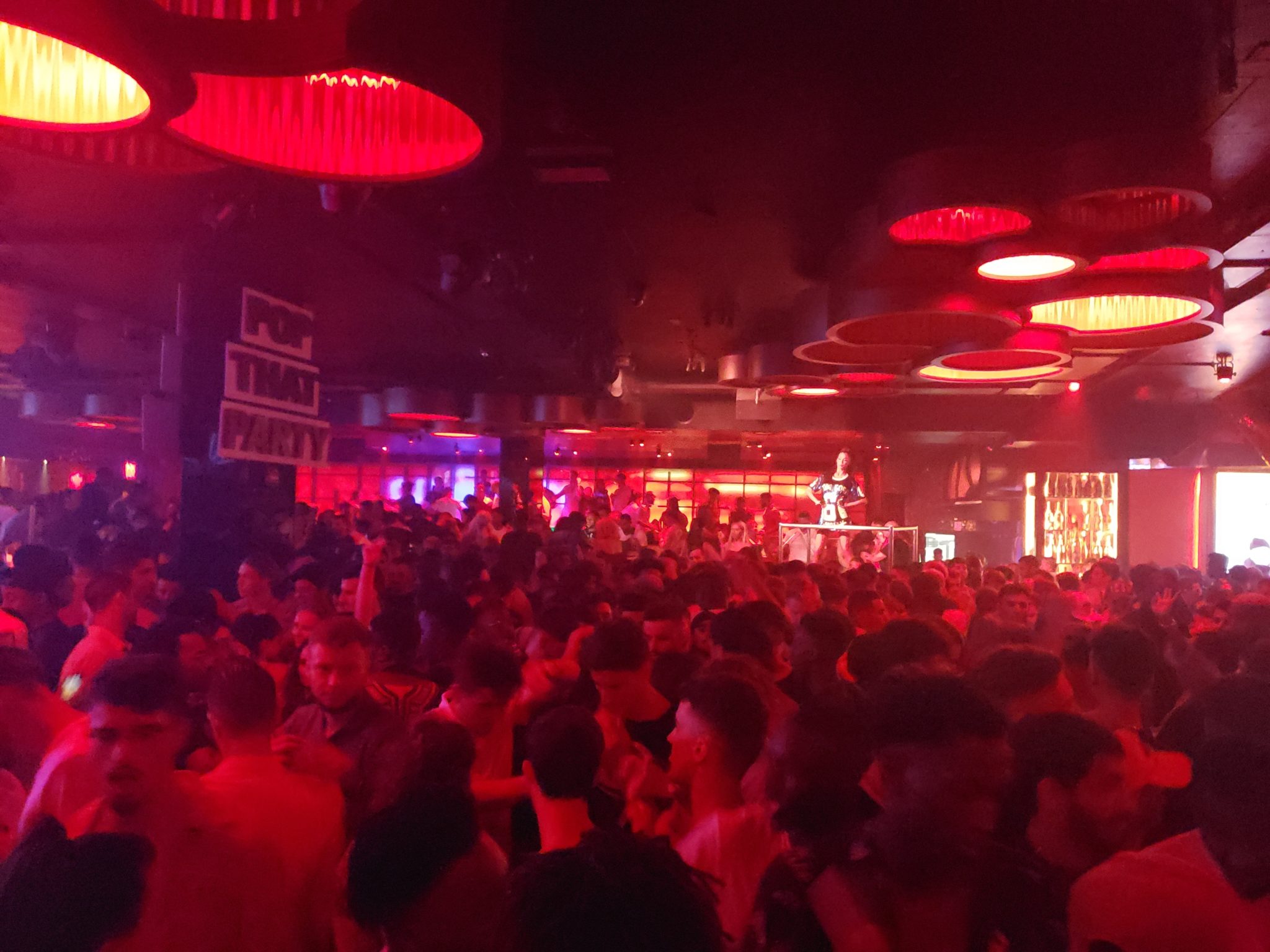 a crowd of people in a room with red lights