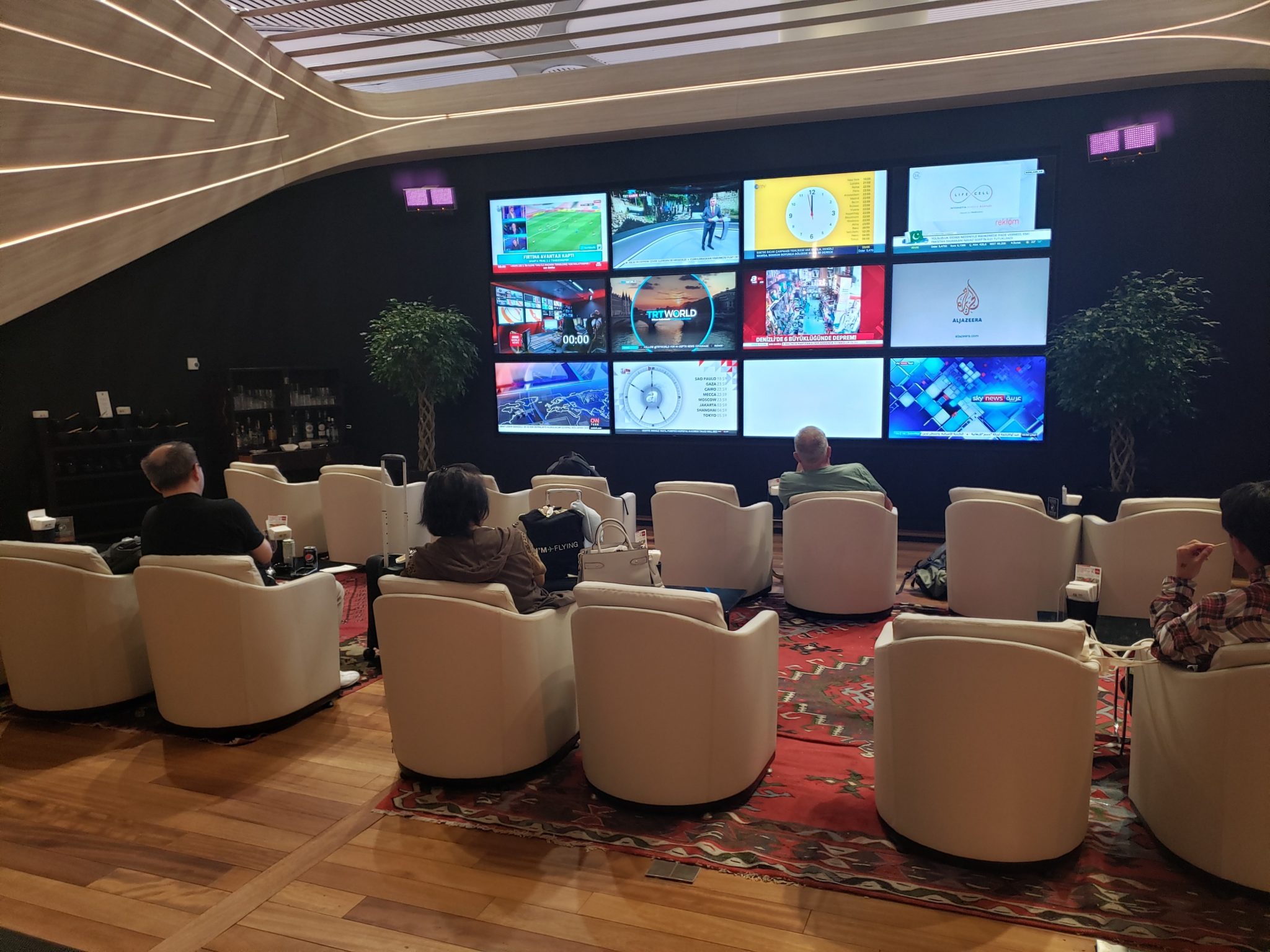 a group of people sitting in chairs in a room with large screens