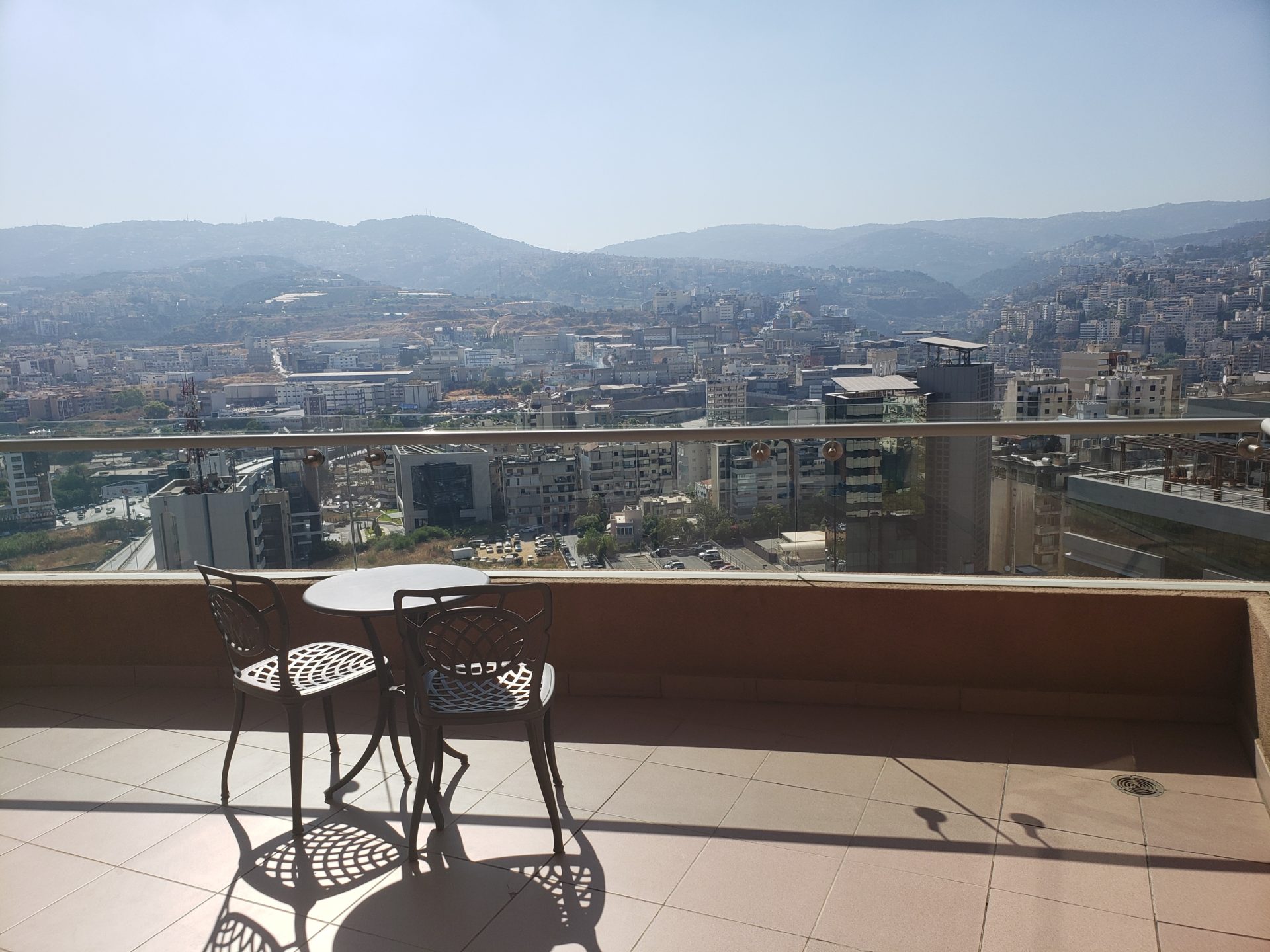 a table and chairs on a balcony overlooking a city