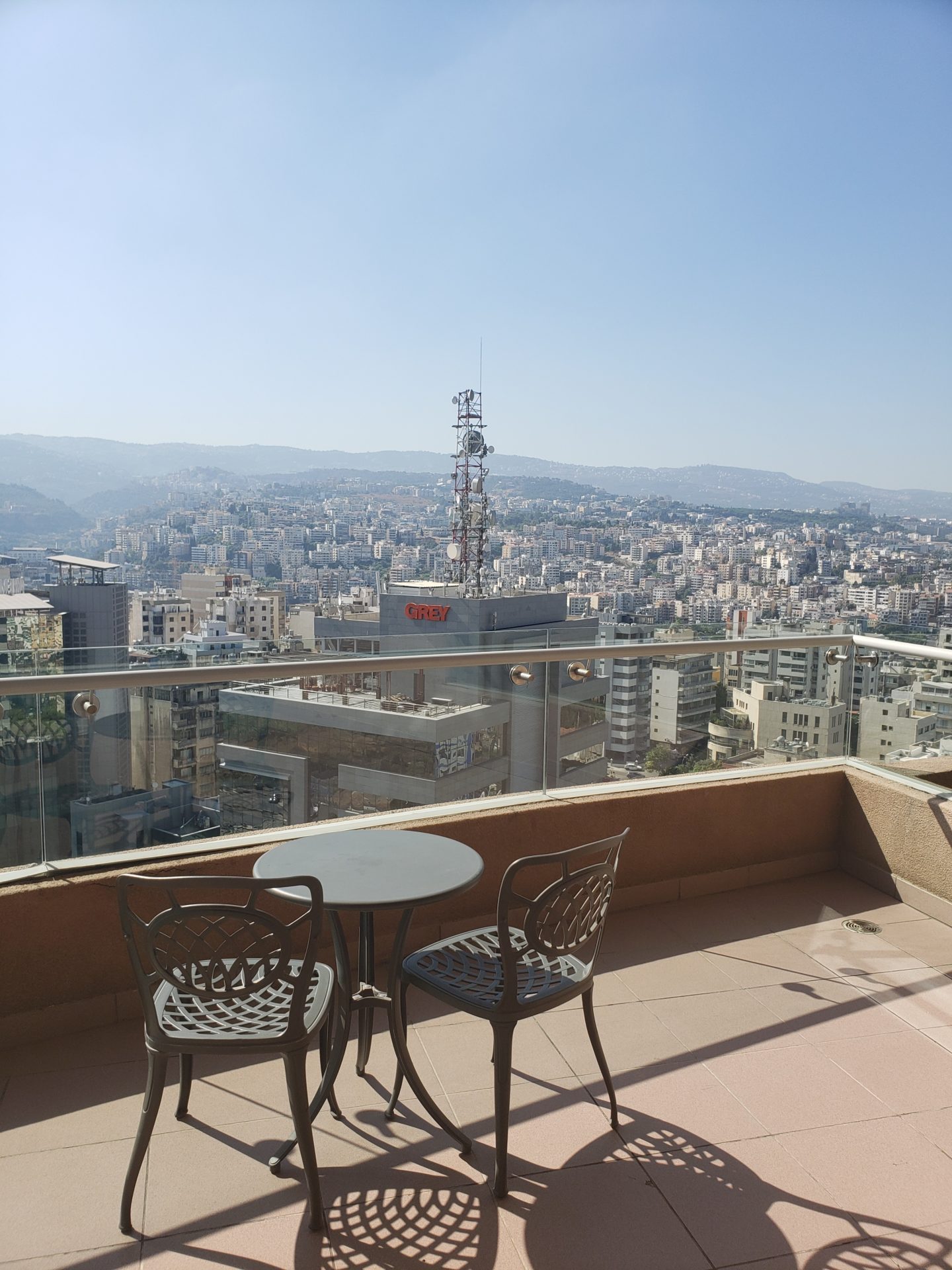 a table and chairs on a balcony overlooking a city