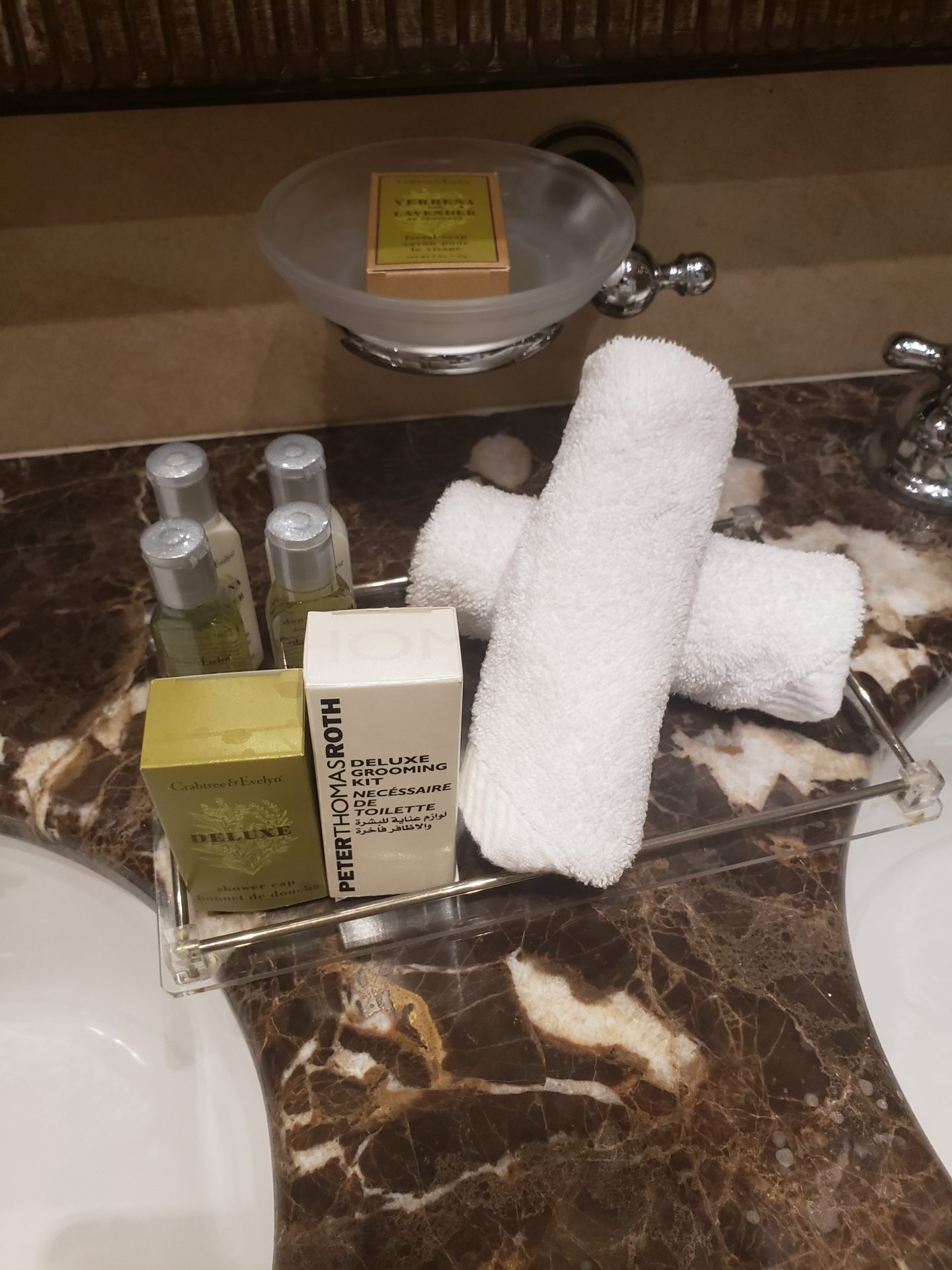 a bathroom sink with a tray of towels and toiletries