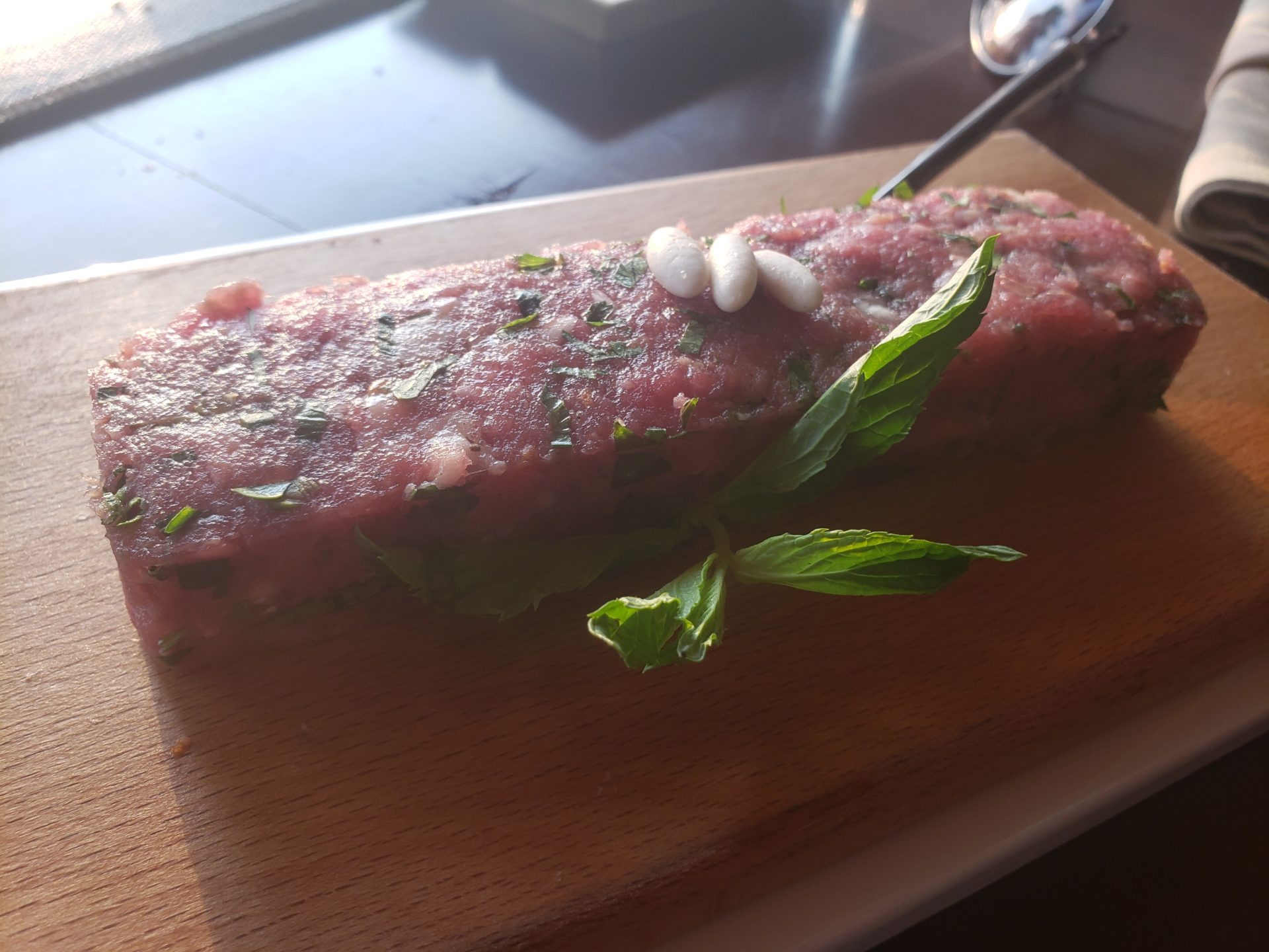a piece of meat with leaves on a wooden board
