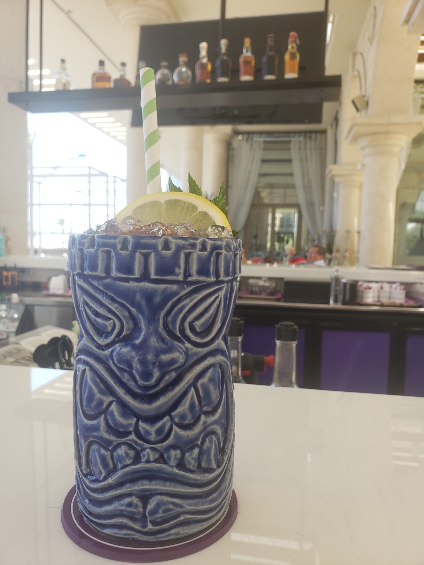 a blue tiki glass with a straw and lemon