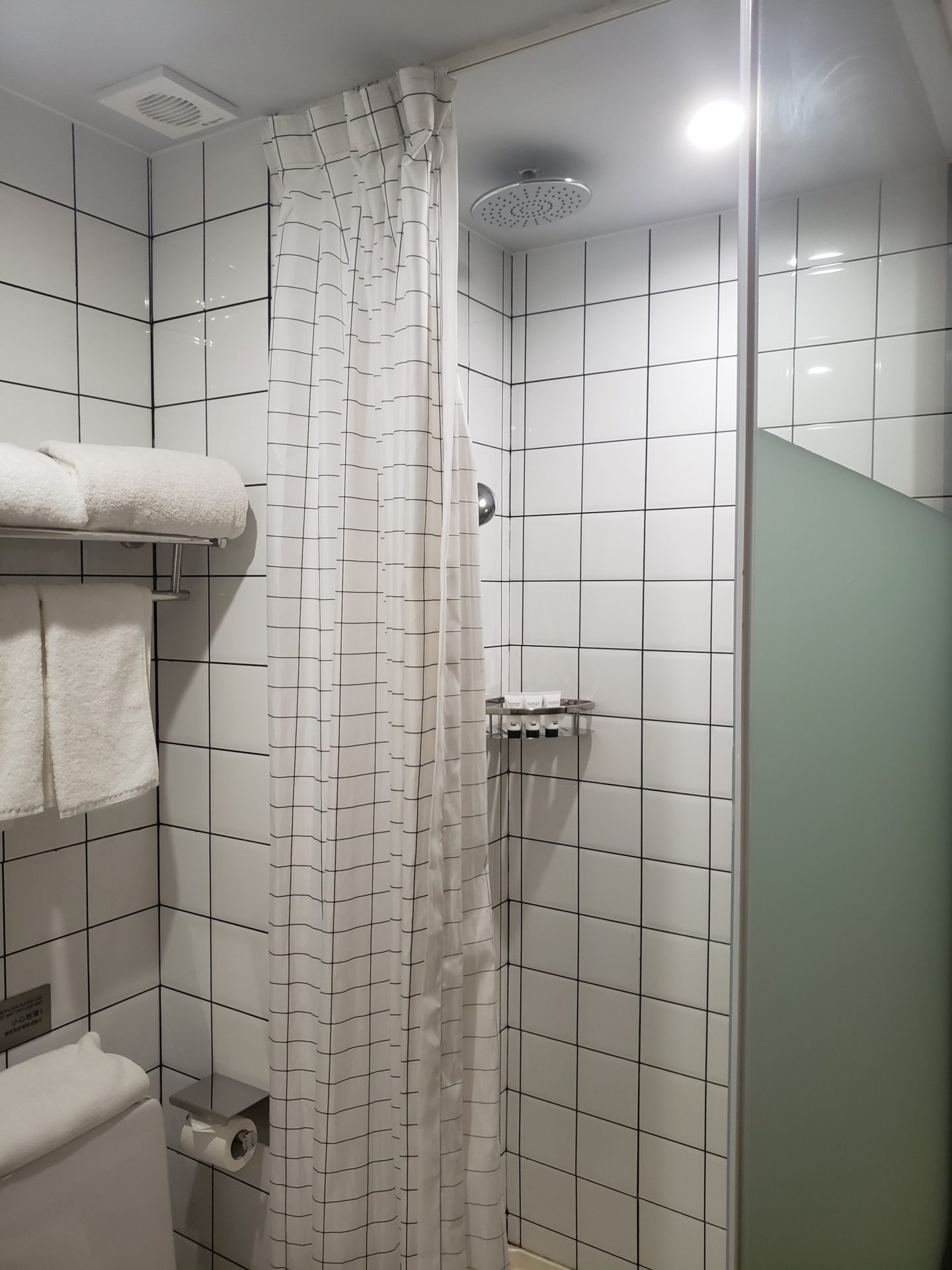 a shower with white tile walls and white towels