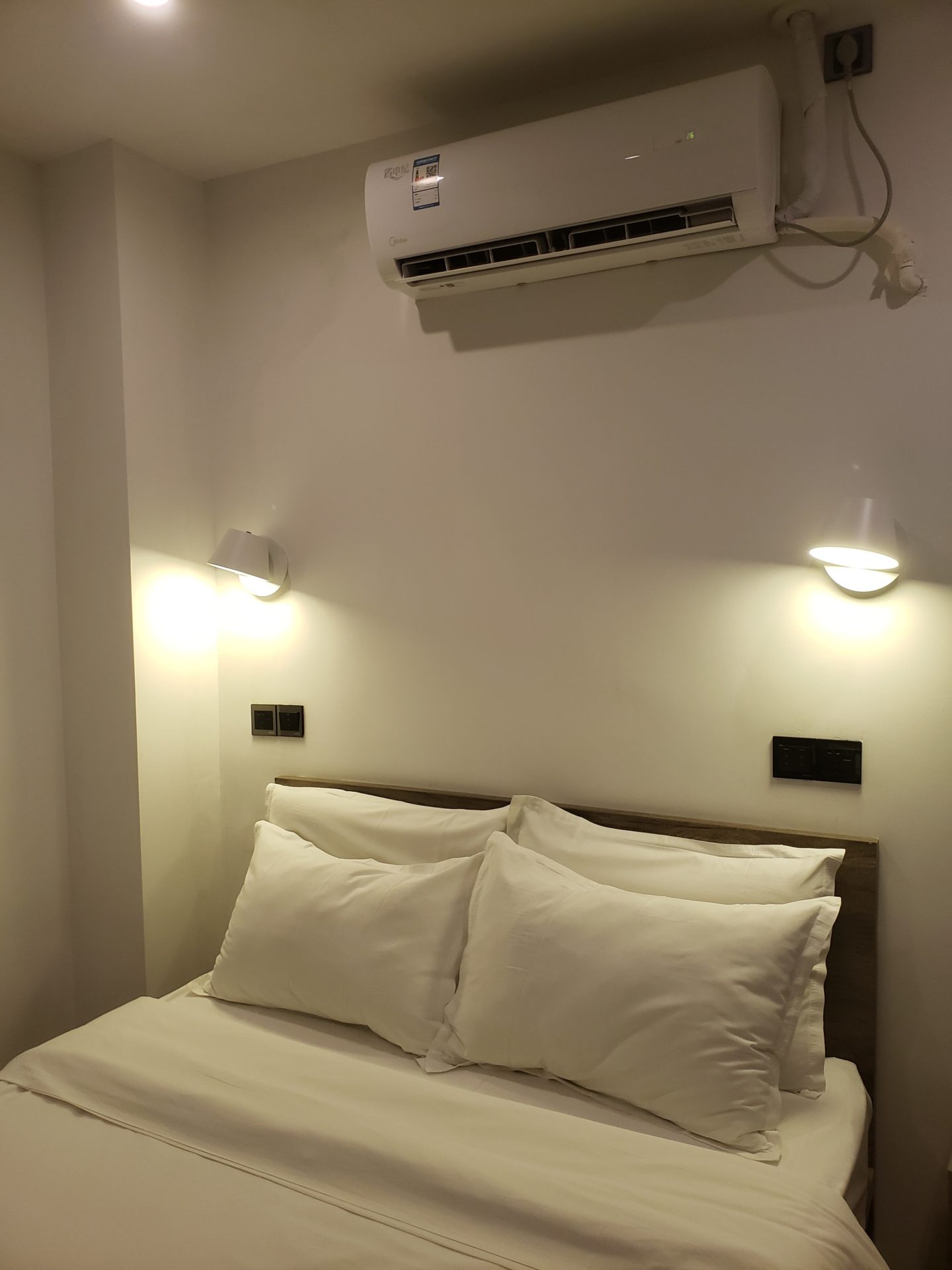 a bed with pillows and a air conditioner above it