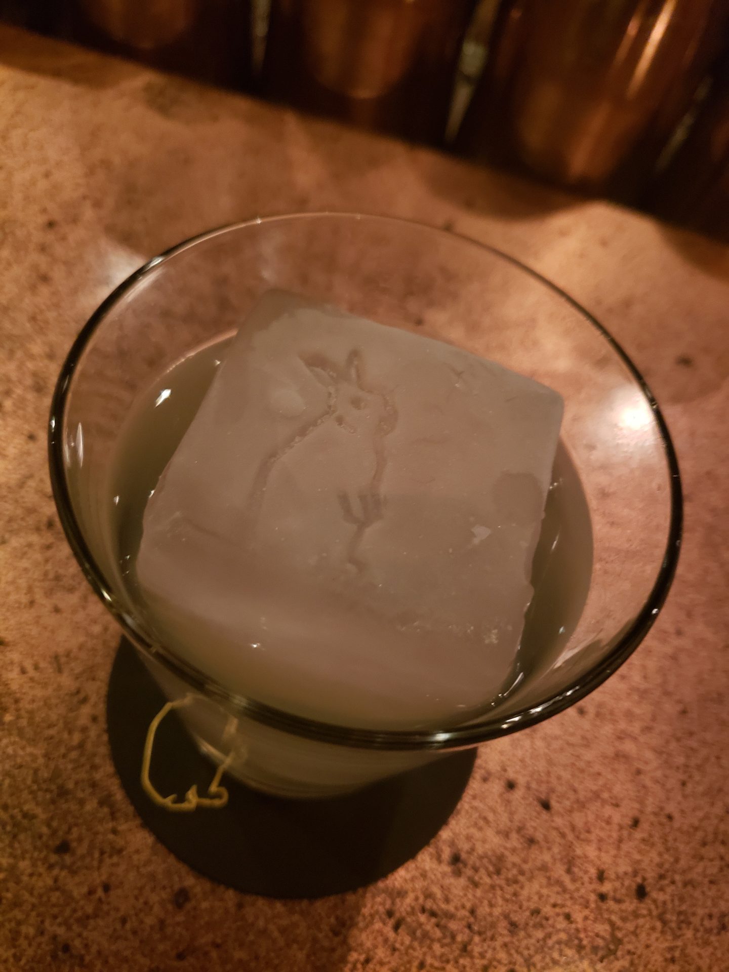 a glass with a drink and ice cube in it