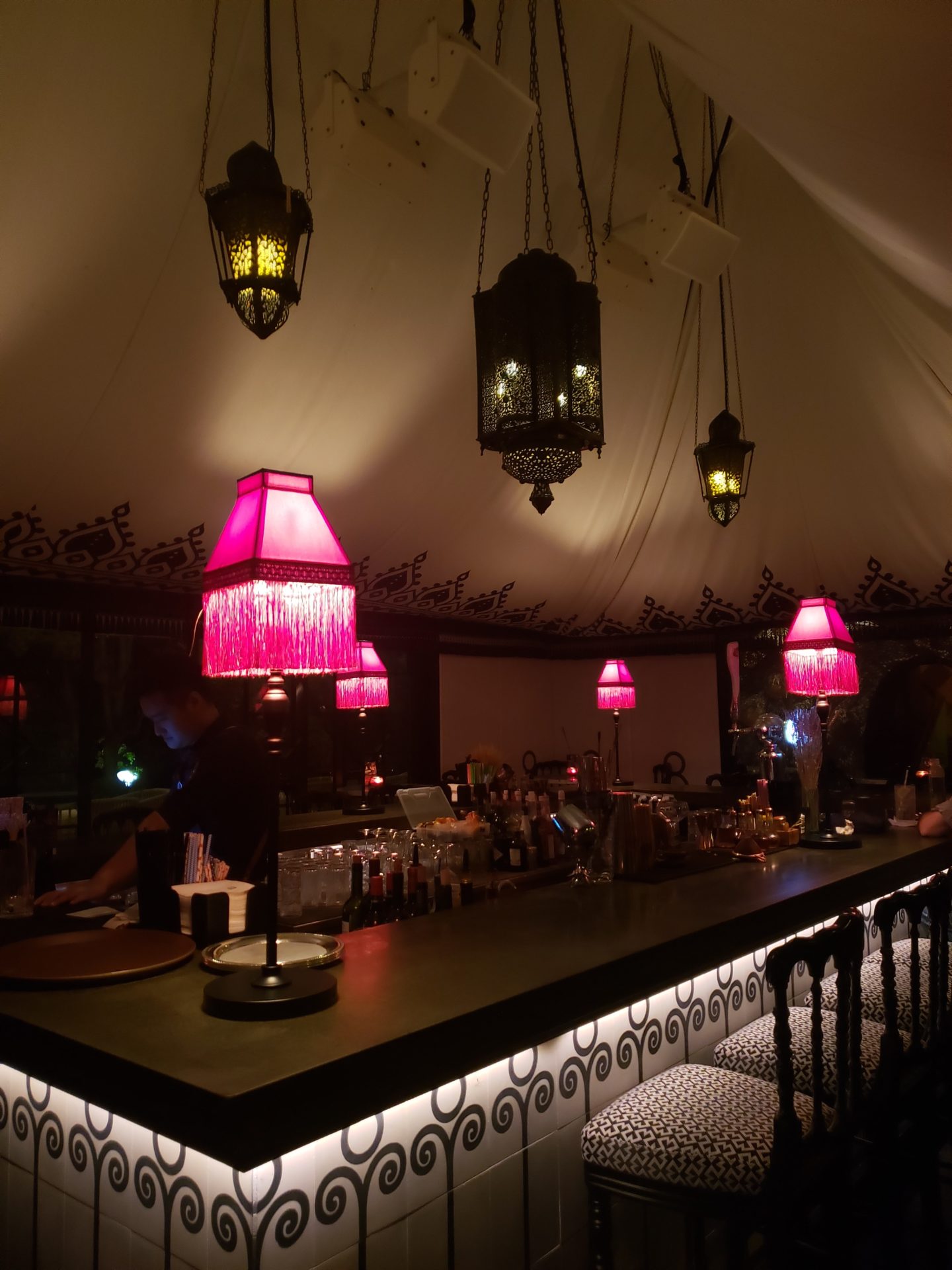 a bar with pink lamps