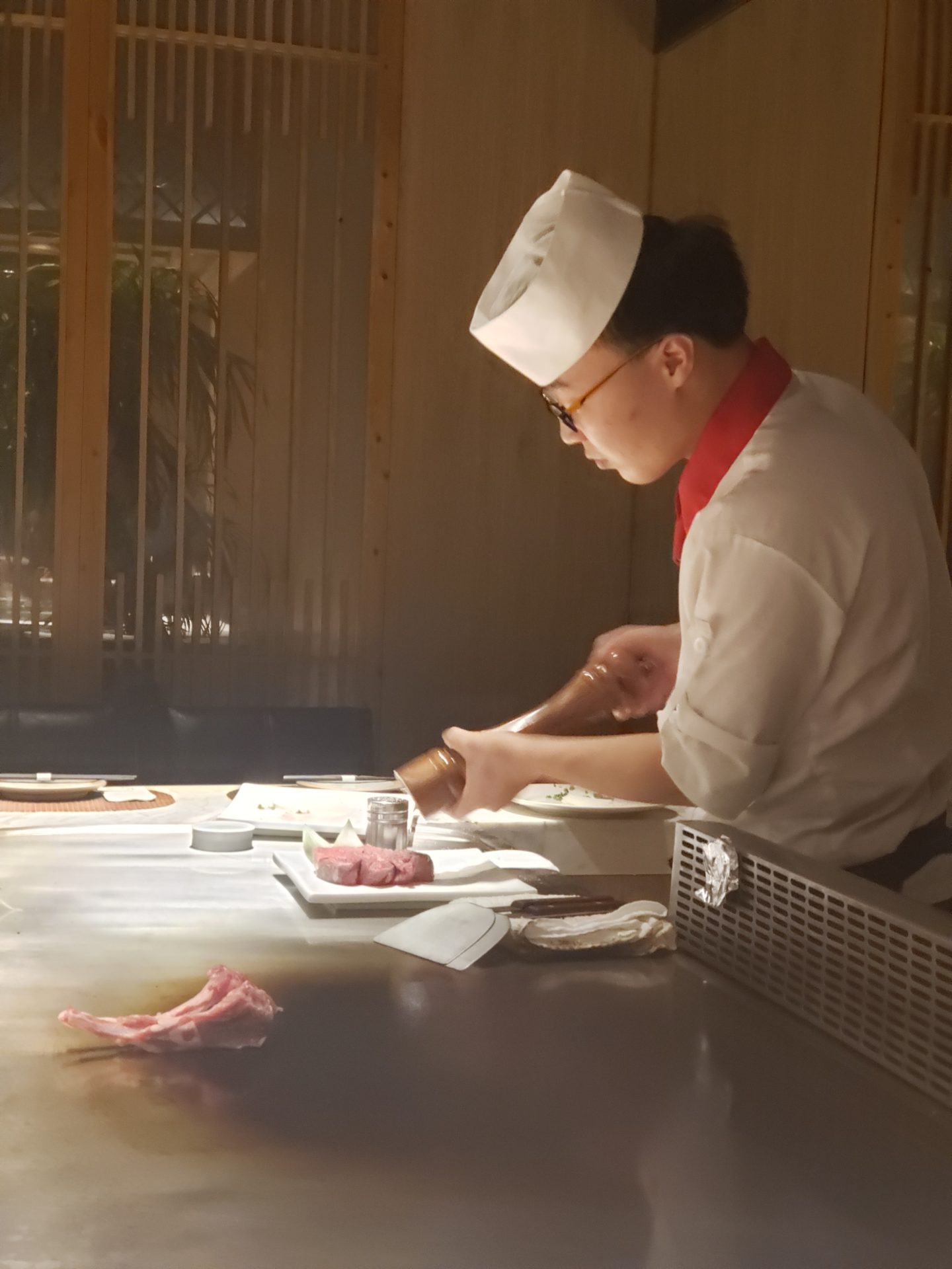 a man in a chef's uniform pouring a salt into a plate of meat