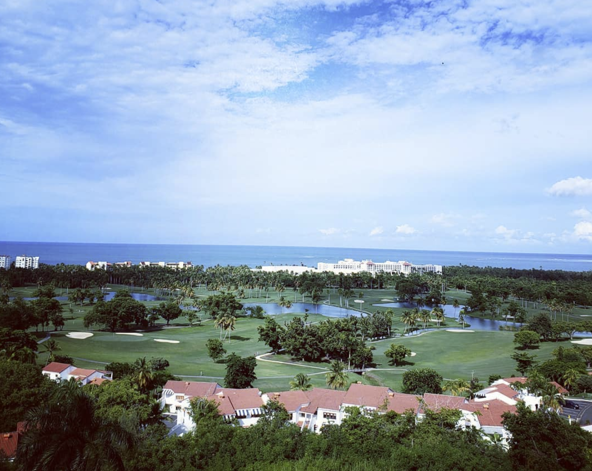a golf course with a large body of water and buildings