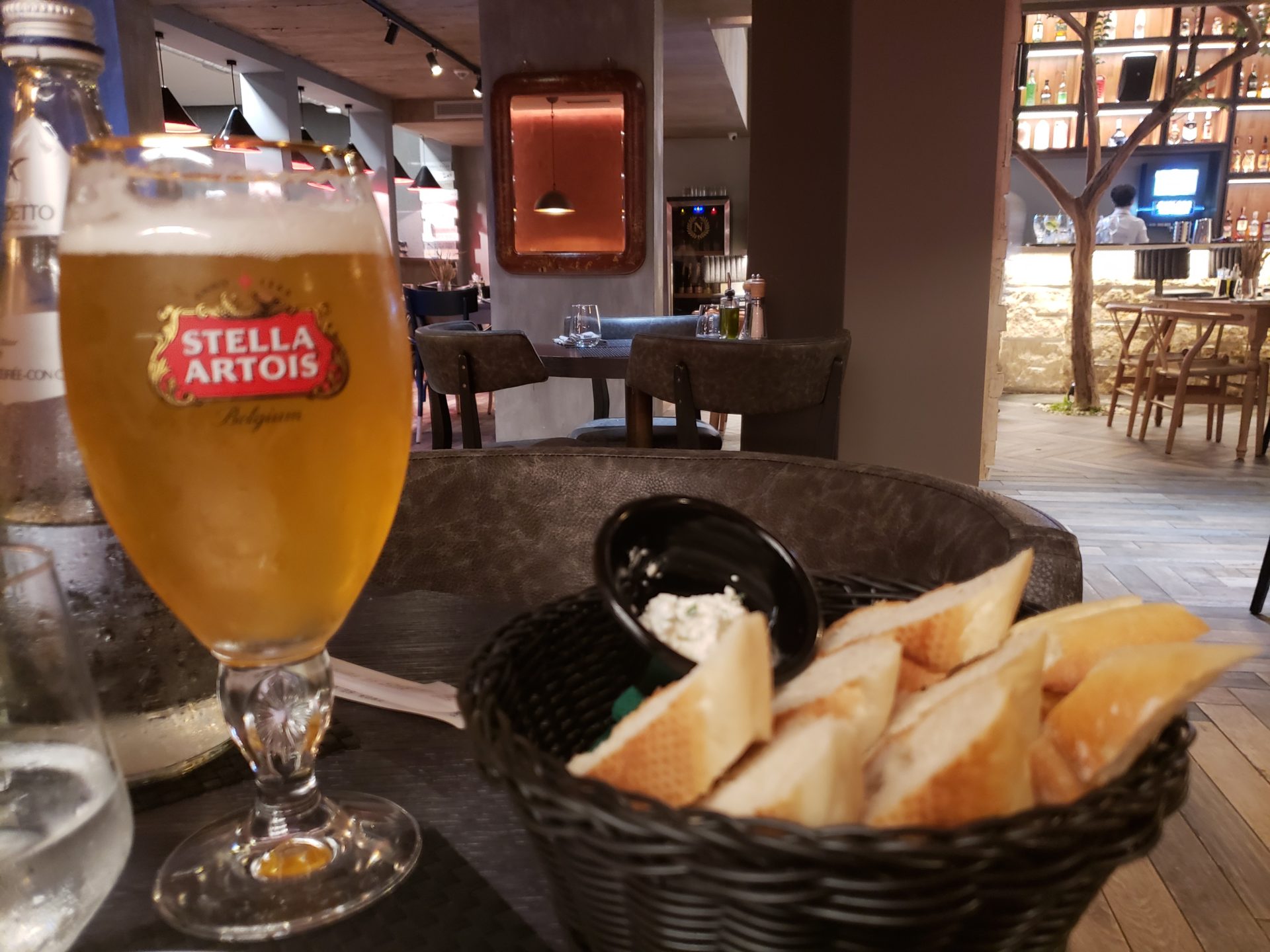 a glass of beer and a basket of bread