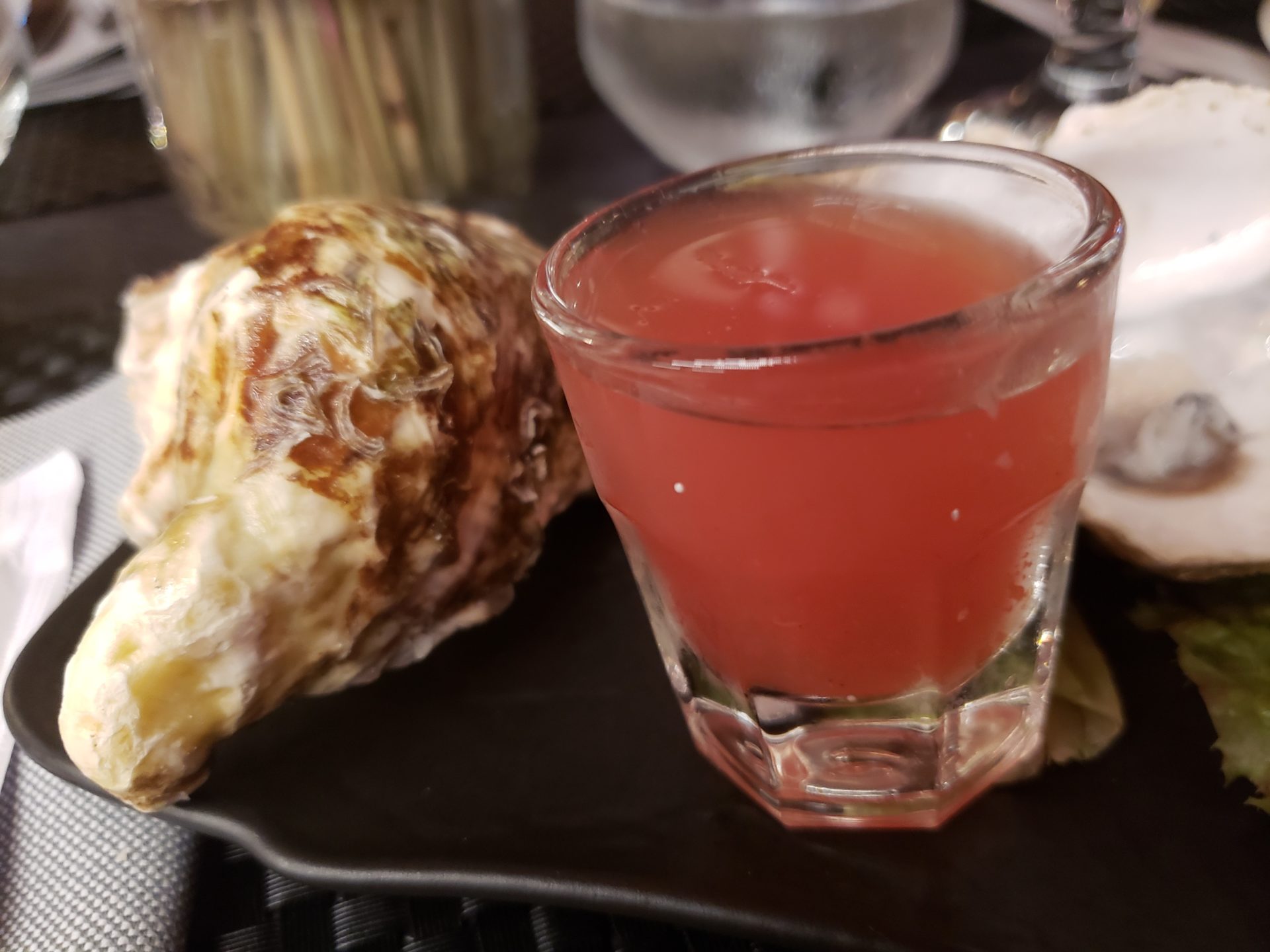 a glass of pink liquid next to a shell