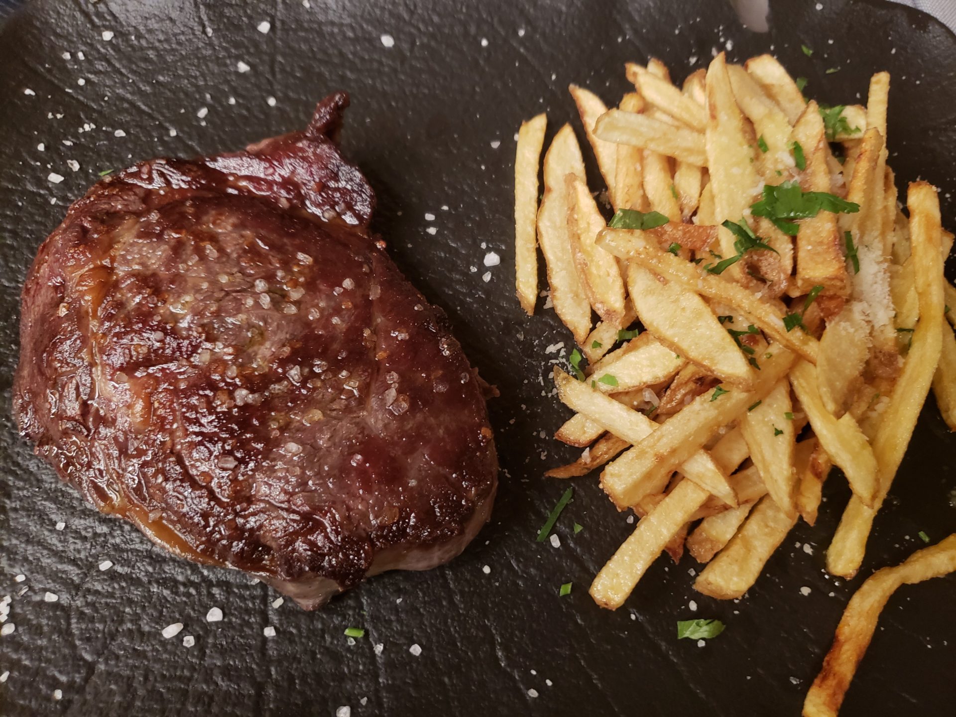 a steak and french fries on a black surface