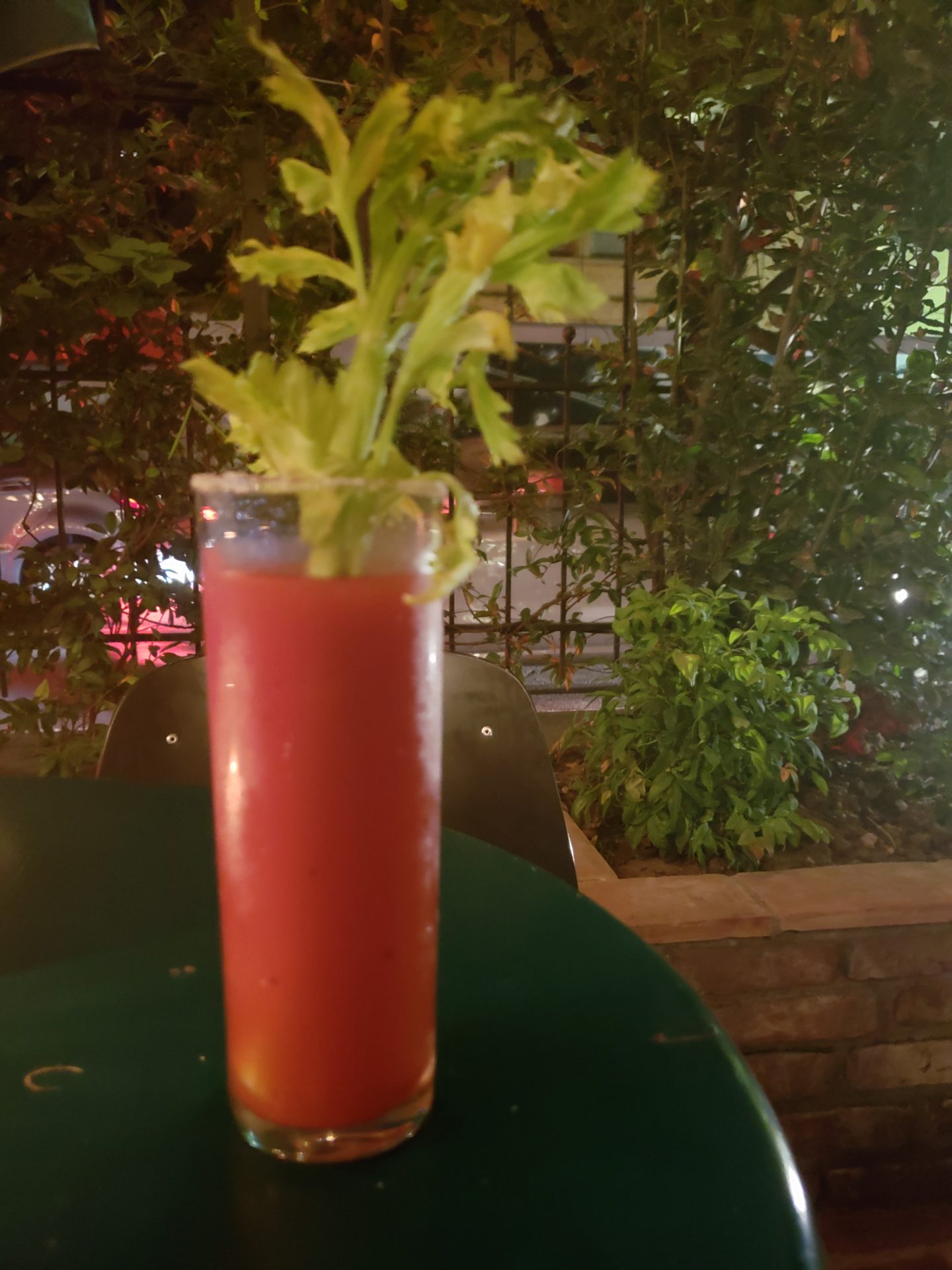 a glass of red liquid with a celery plant on top