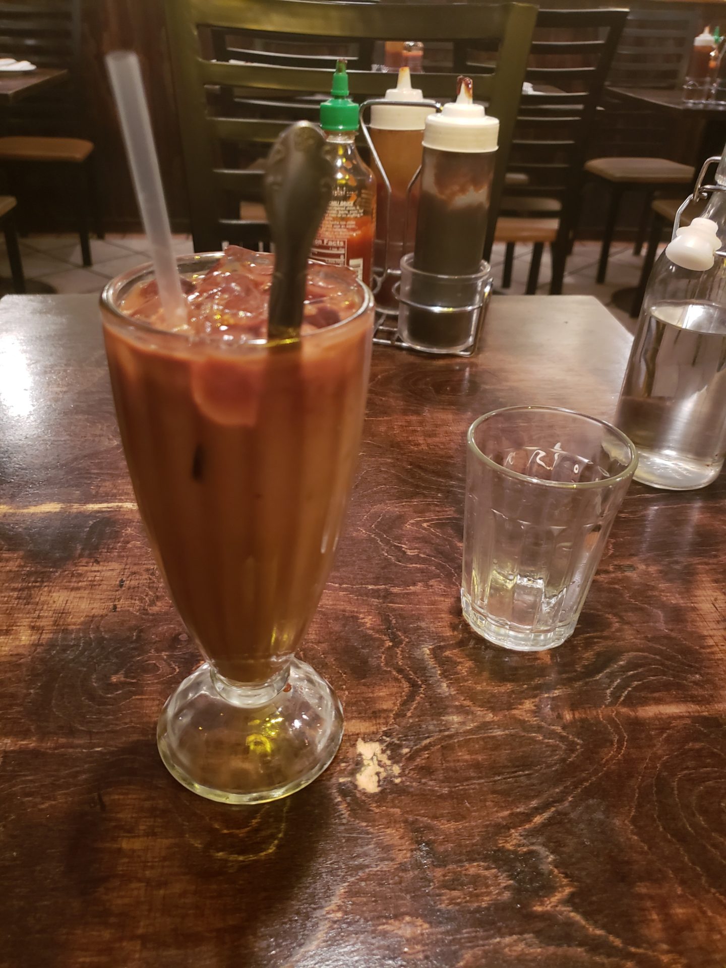 a glass of brown liquid with a spoon on a table