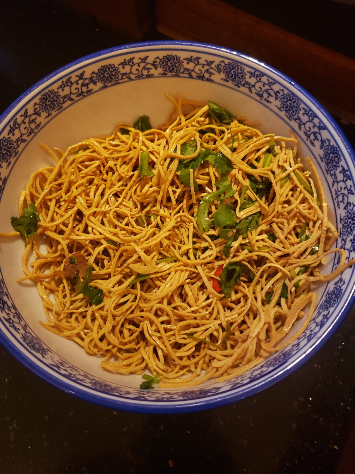 a bowl of noodles with green onions and peppers