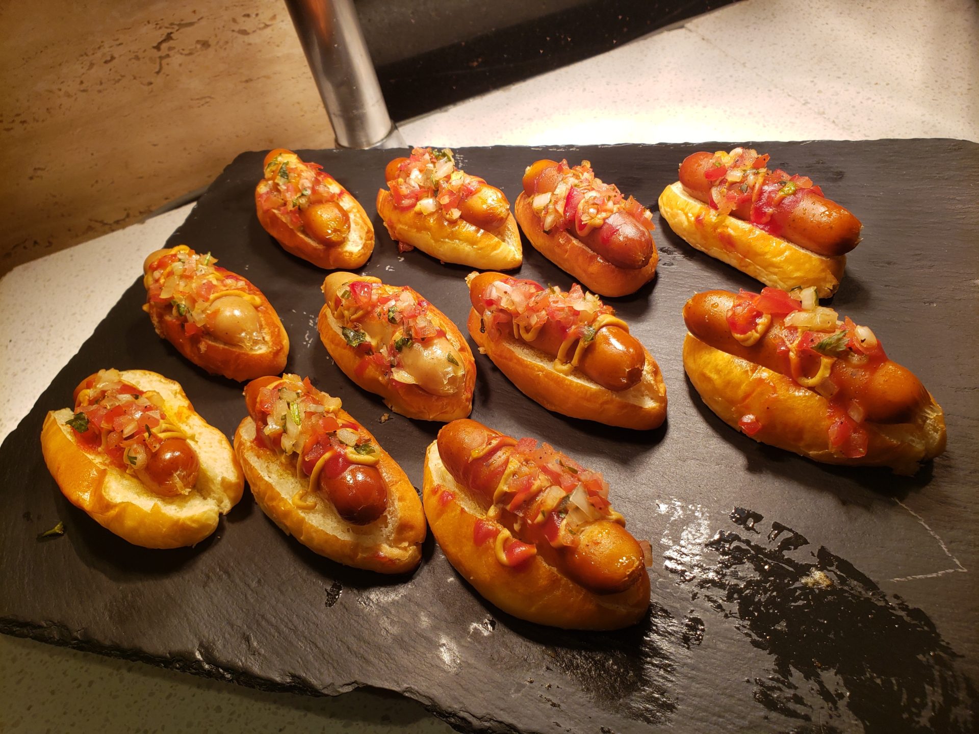 a group of hot dogs on a black tray