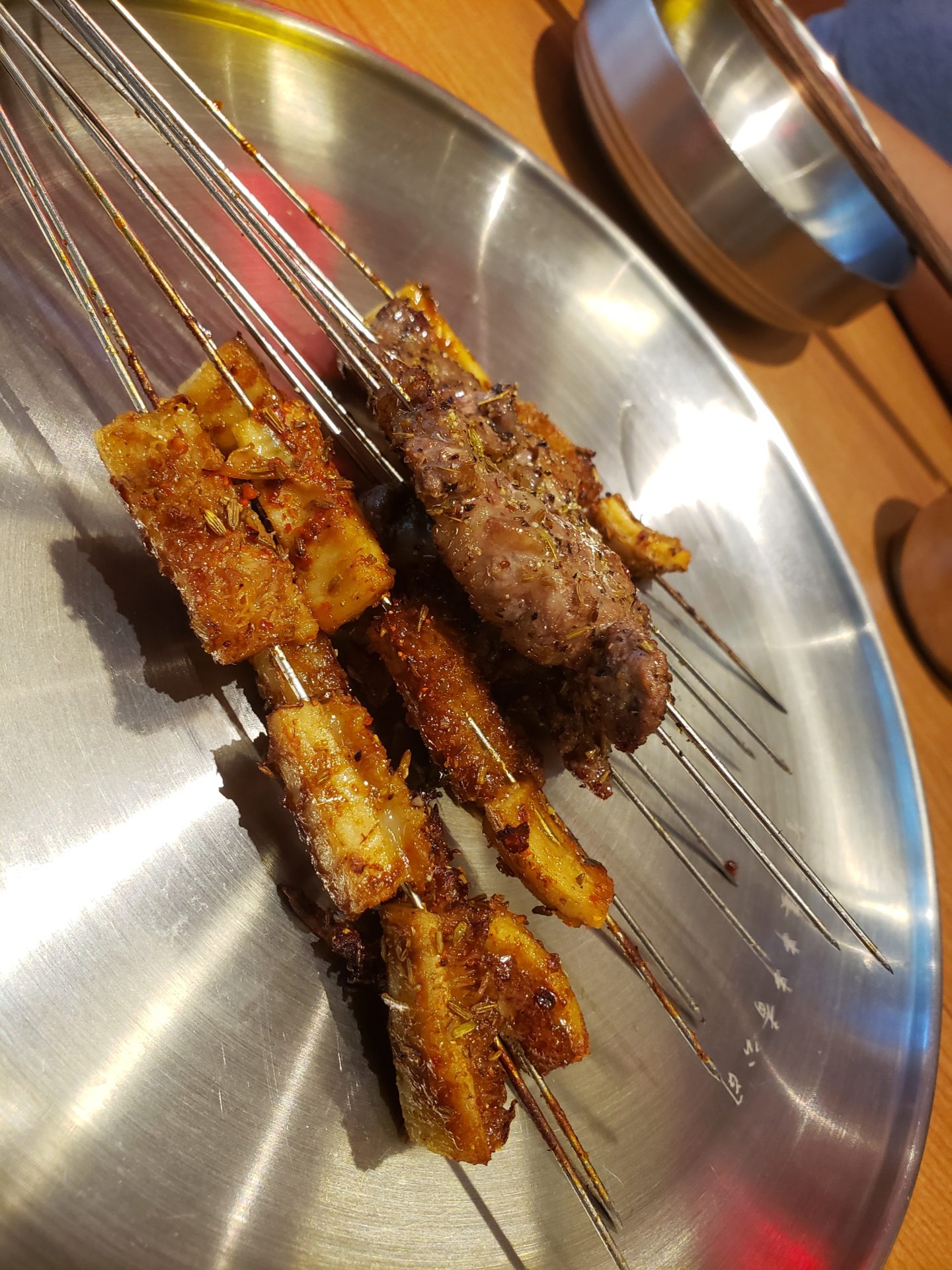 skewers on a metal plate with meat on it