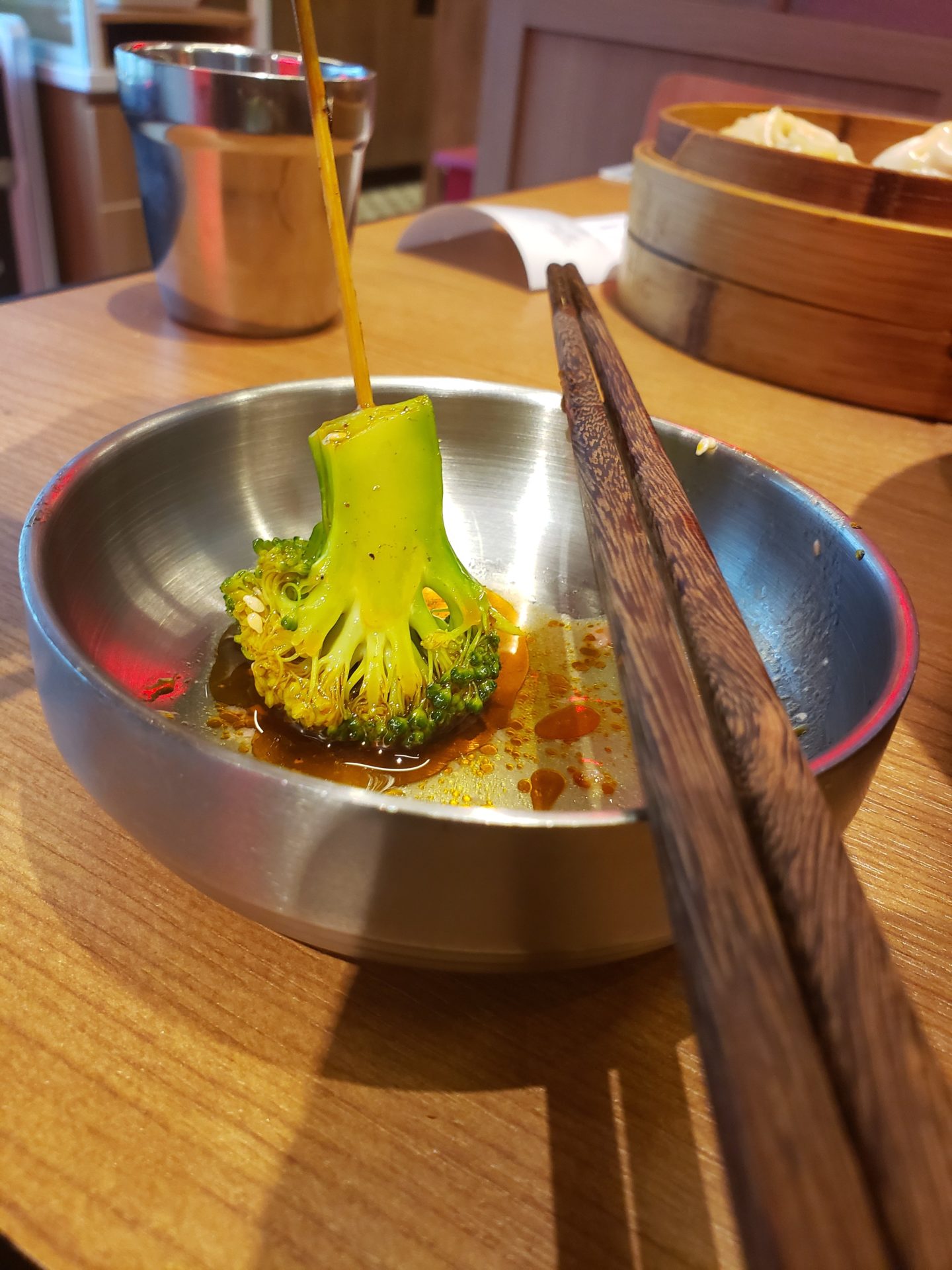 a bowl of broccoli with chopsticks