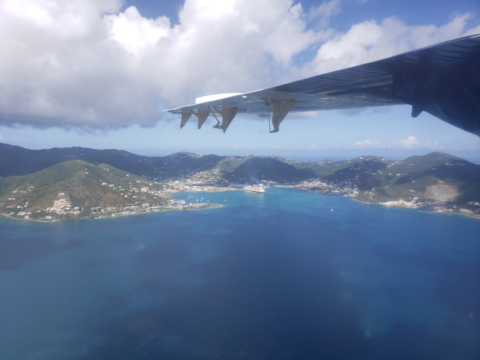 an airplane wing over a body of water with land and buildings