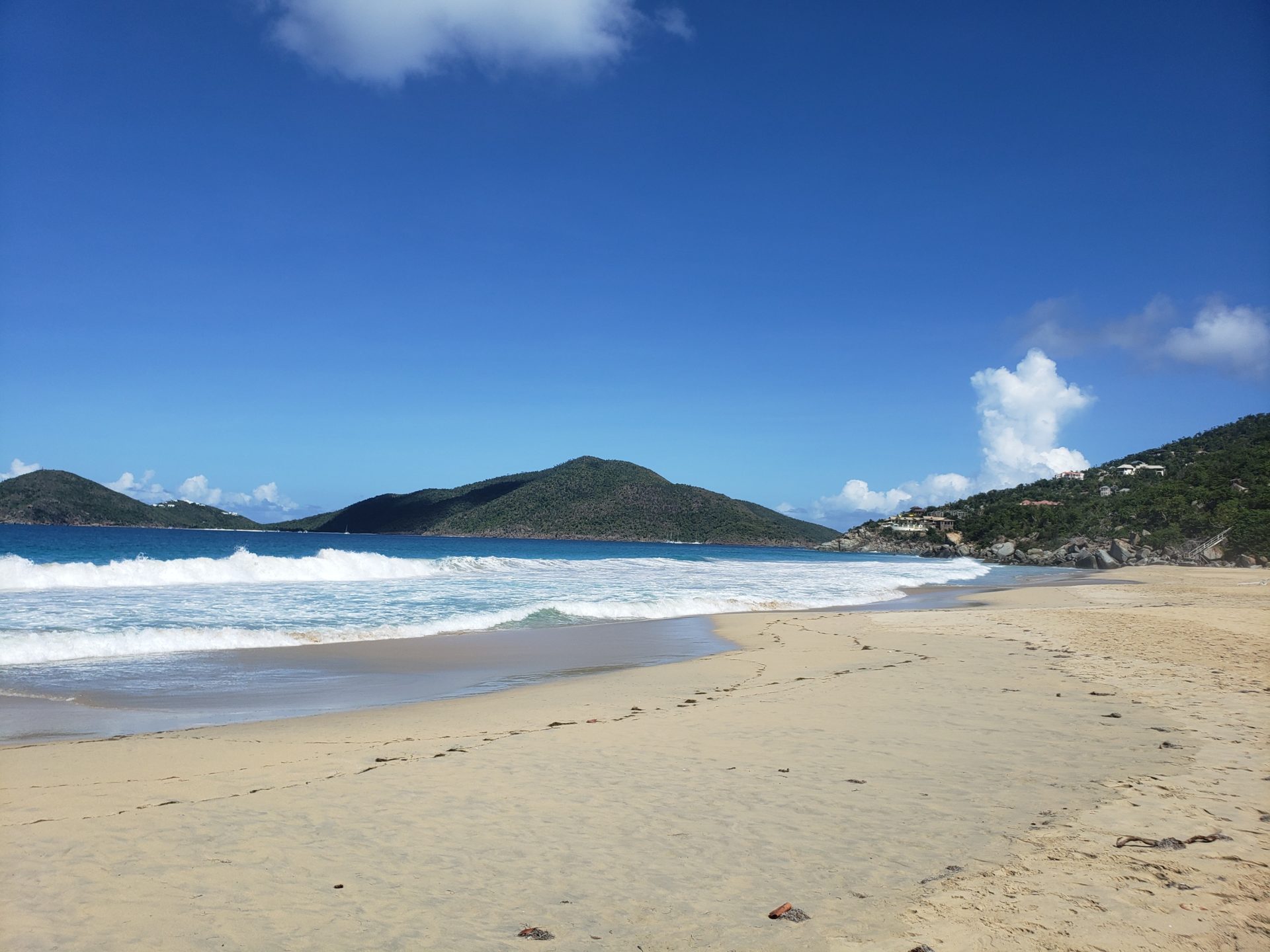 a beach with waves and hills in the background