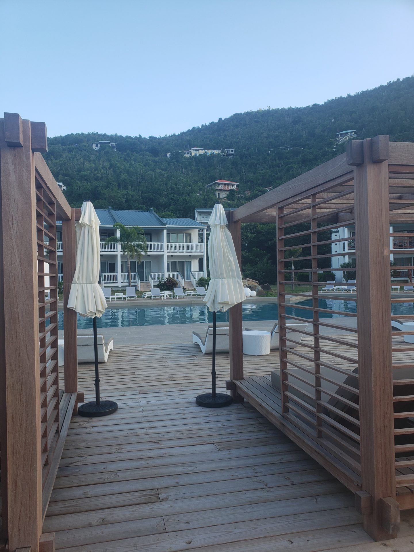 a wooden deck with umbrellas and a pool in the background