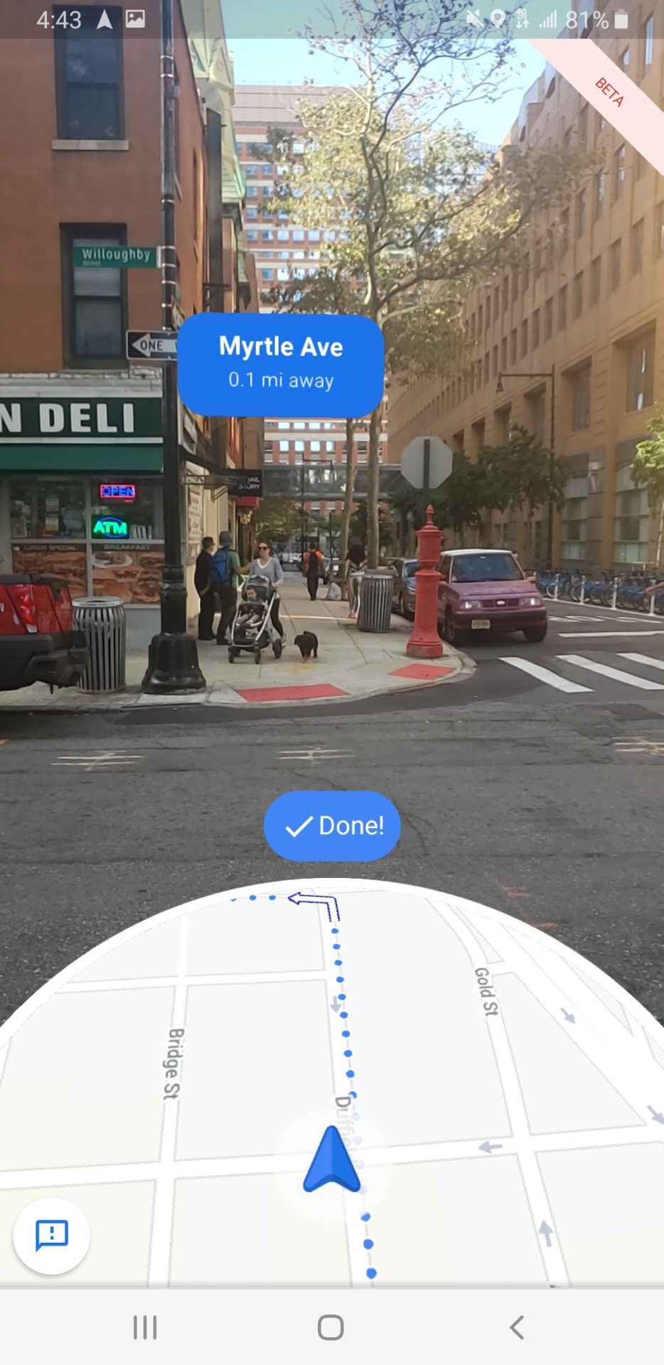 a screenshot of a phone screen showing a street corner with cars and people