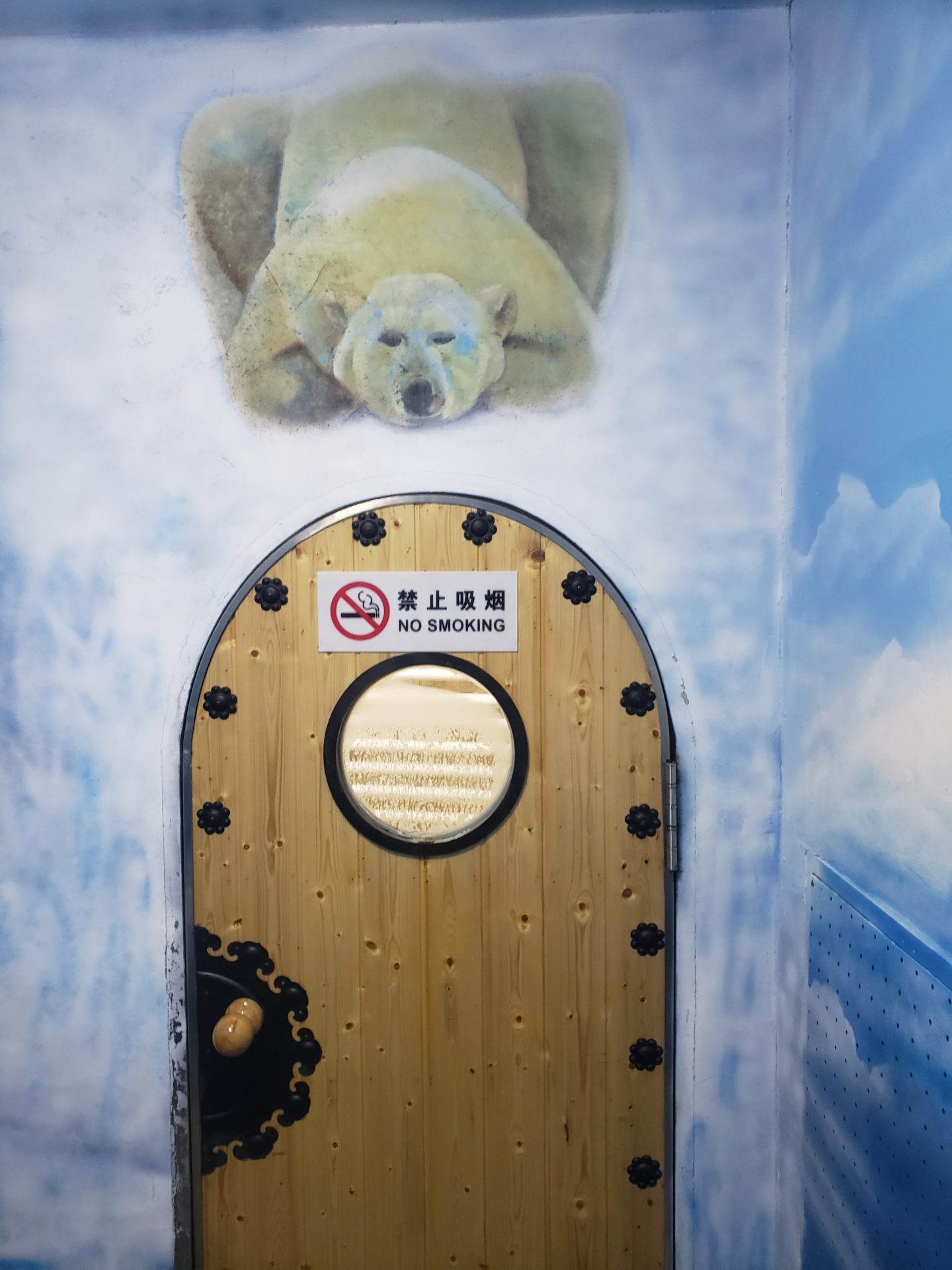 a door with a round window and a bear on the wall